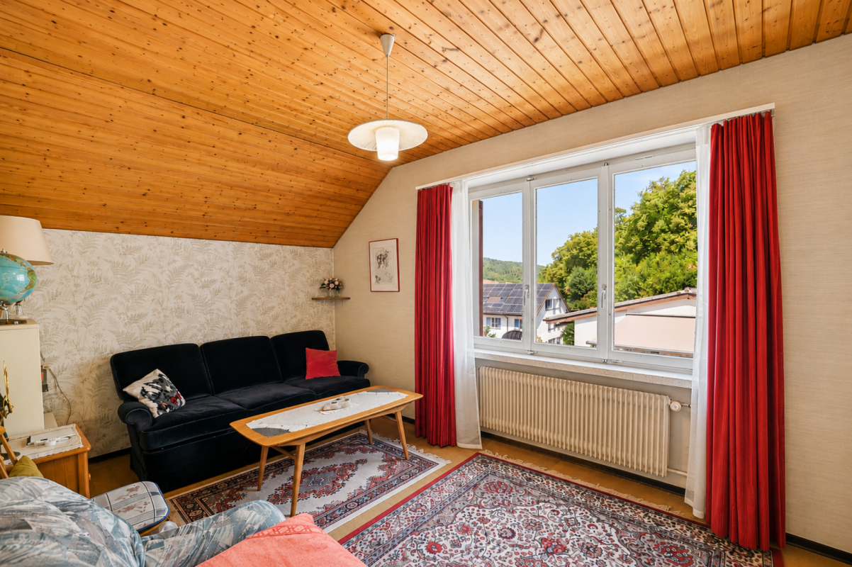 Gemütliches Wohnzimmer mit Holzdecke und großem Fenster
