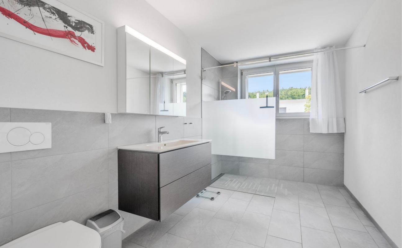 Modernes Badezimmer mit Oberlichtfenster und Glasabtrennung