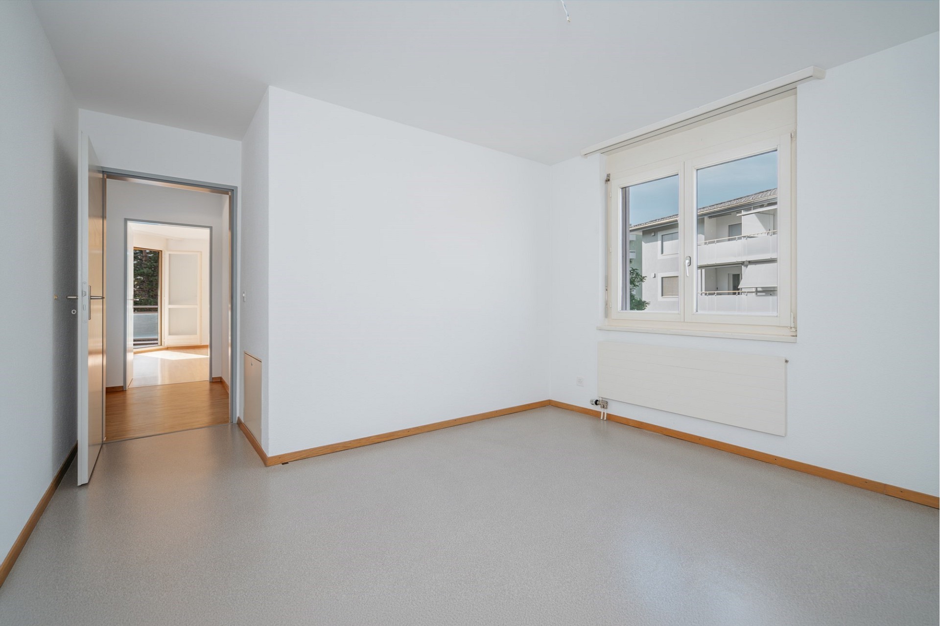 Helles, leeres Zimmer mit Fenster und Blick ins Gegenüber