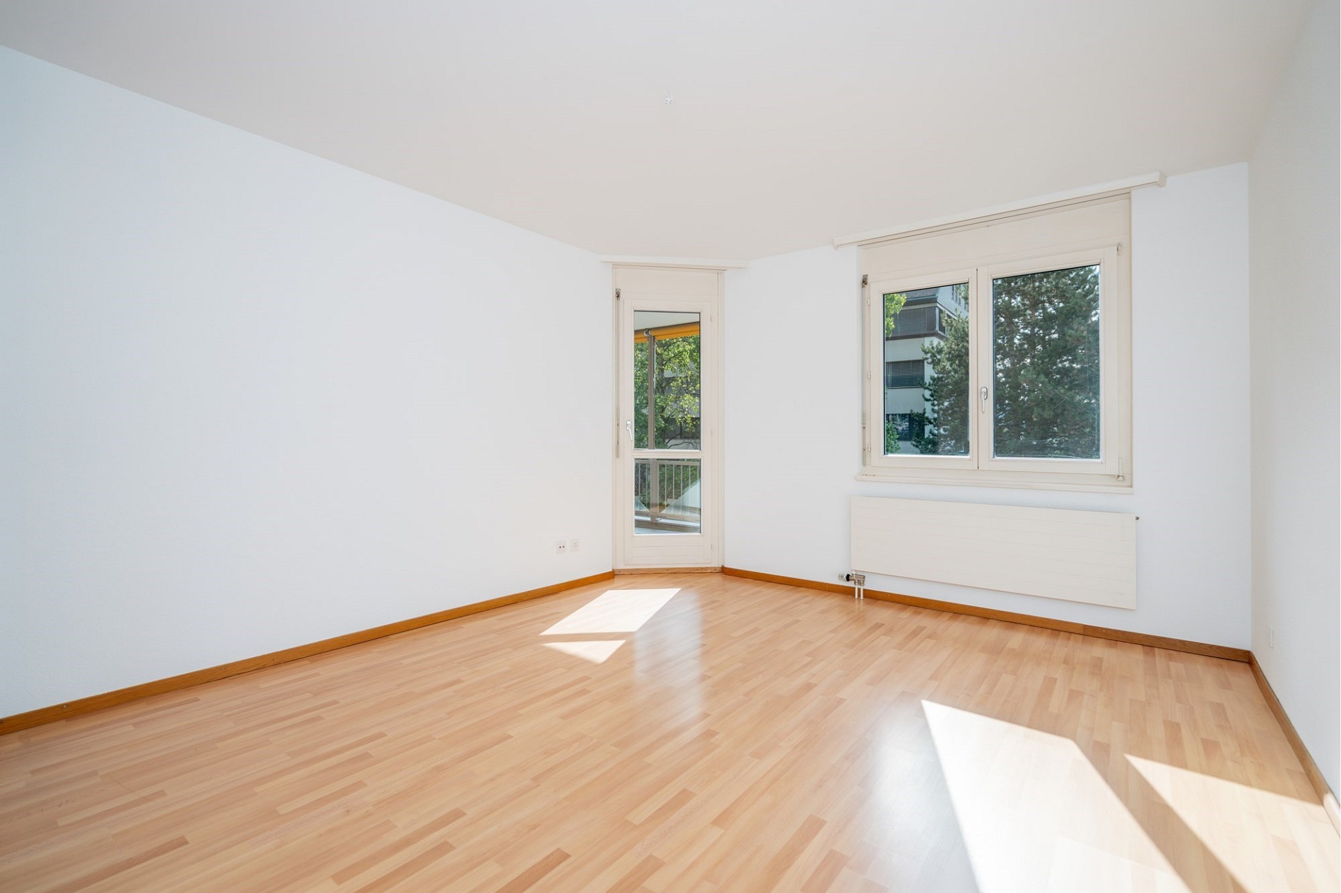 Leerer, heller Wohnraum mit Balkon- bzw. Fensterelementen