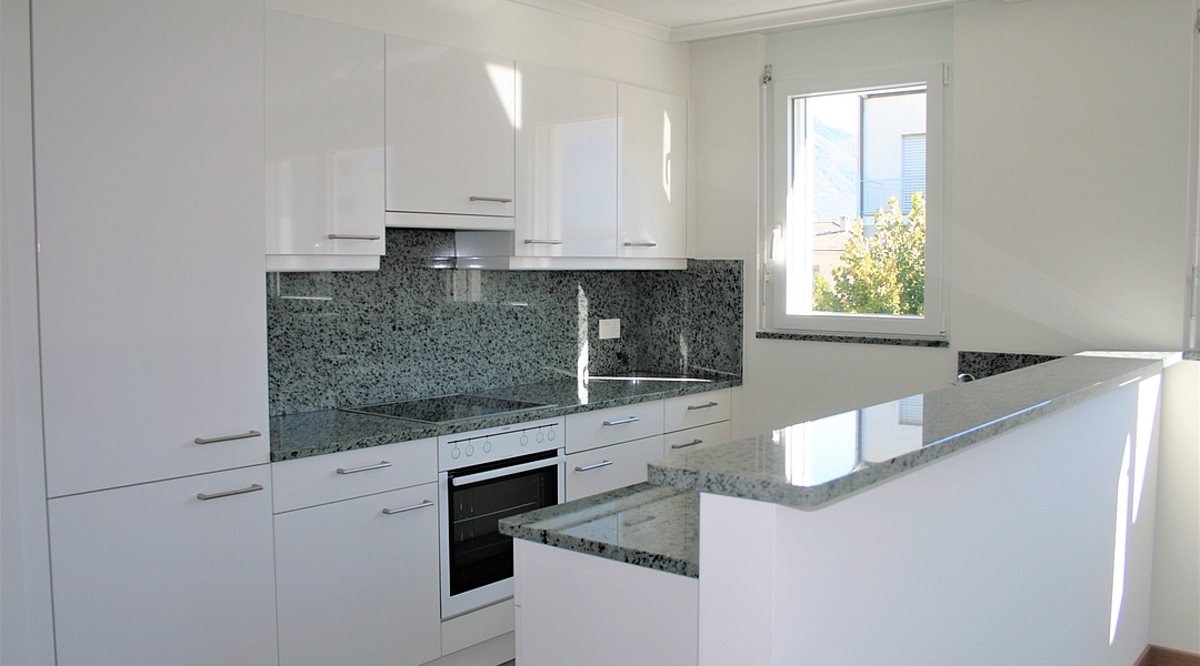 Moderne weiße Küche mit Fenster und Granitarbeitsplatte