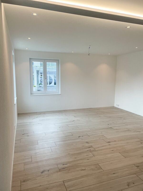 Leerer, modern renovierter Wohnraum mit Parkett und Fenster