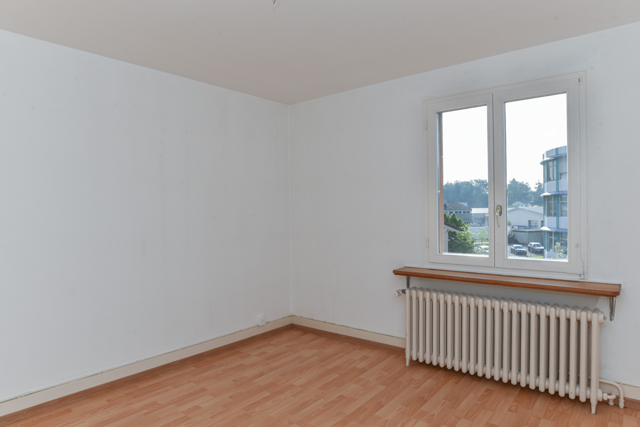 Helles leeres Zimmer mit Fenster und Heizkörper