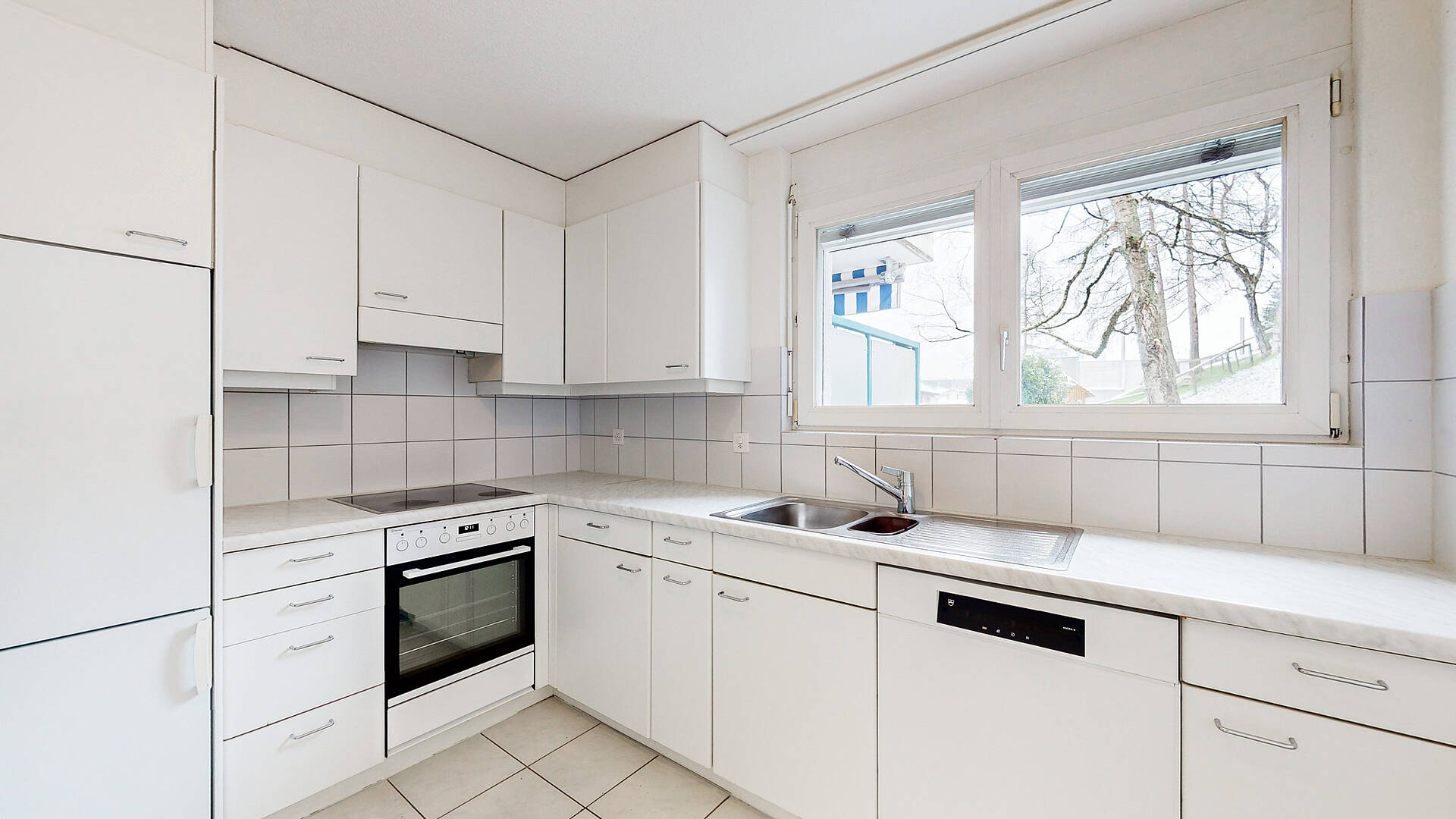 Helle weiße Einbauküche mit Fensterblick
