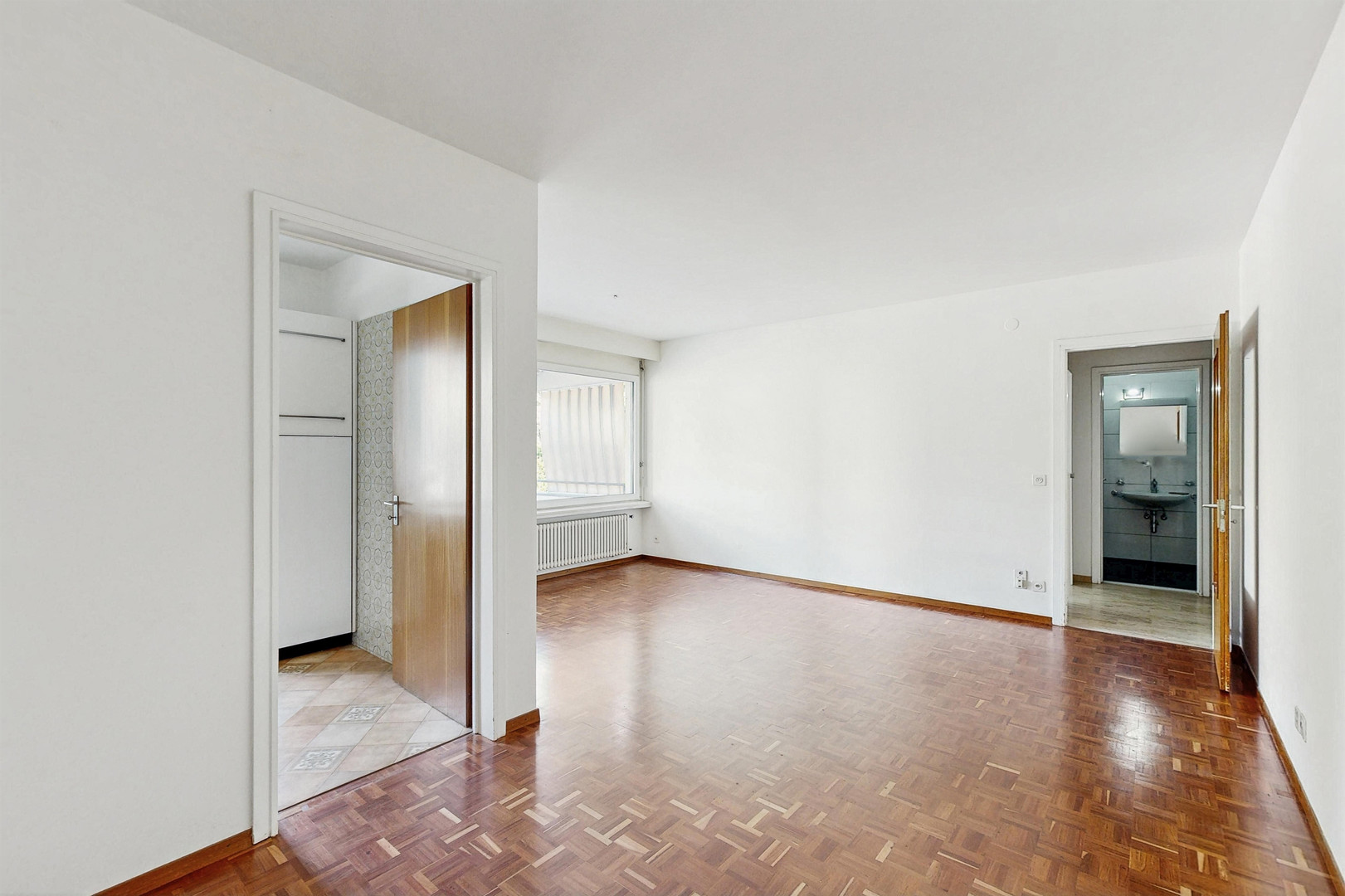 Helles, leeres Zimmer mit Parkettboden