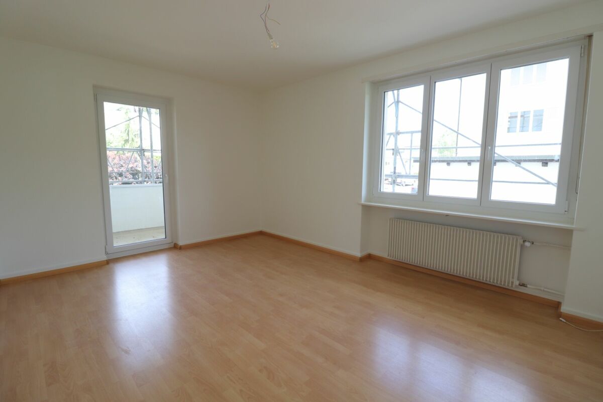 Heller leerer Wohnraum mit Balkon und großen Fenstern