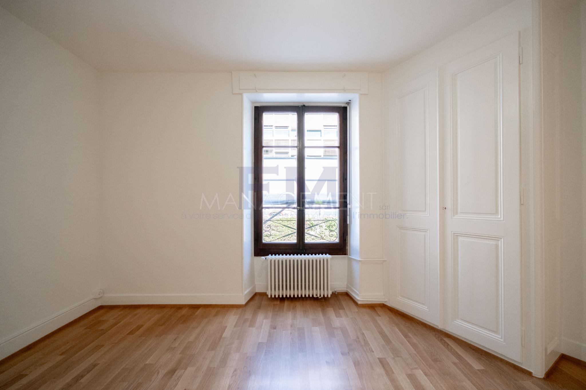 Helles, leeres Zimmer mit Holzfußboden und Fenster