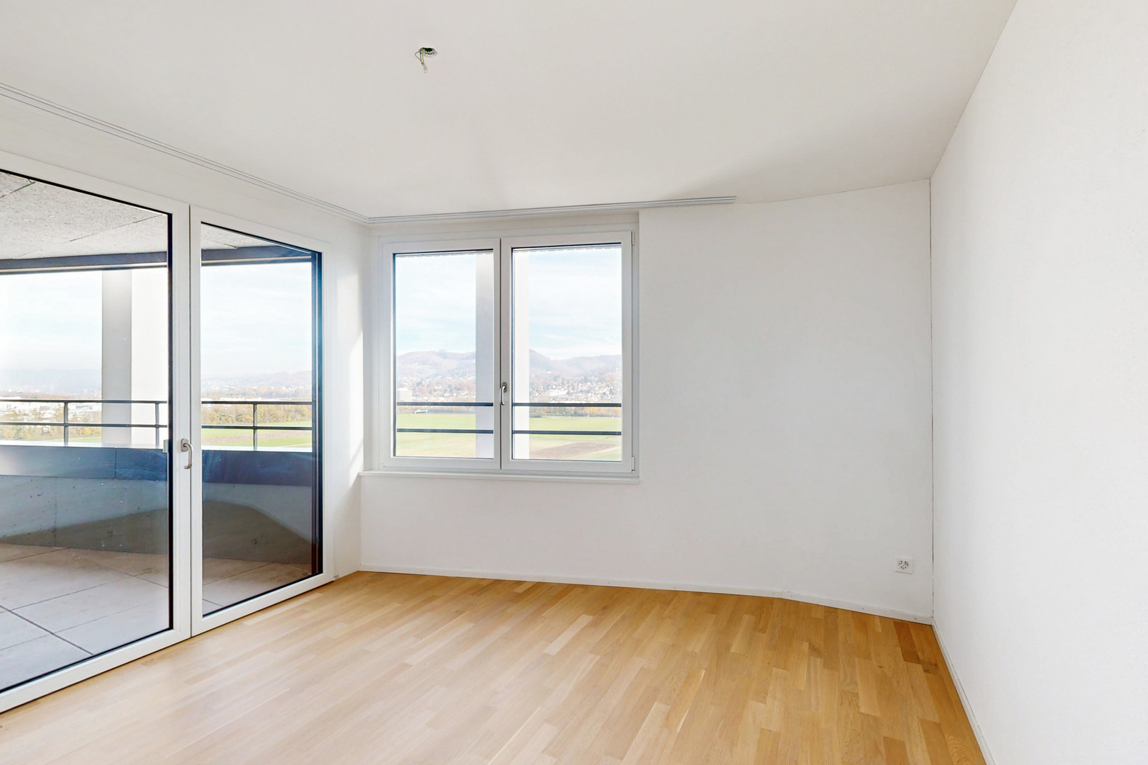 Leerer heller Wohnraum mit Balkon und Blick ins Grüne