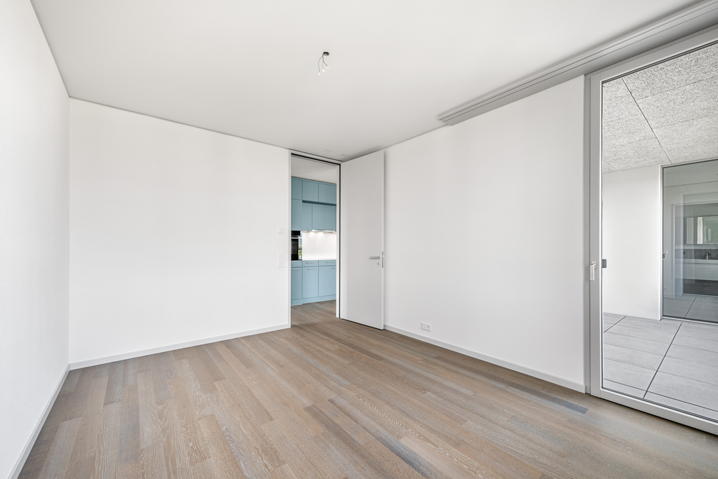 Leeres, modern renoviertes Zimmer mit Zugang zu Küche und Loggia
