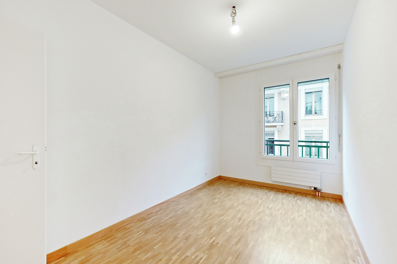 Leerer heller Raum mit Parkett und Fenster