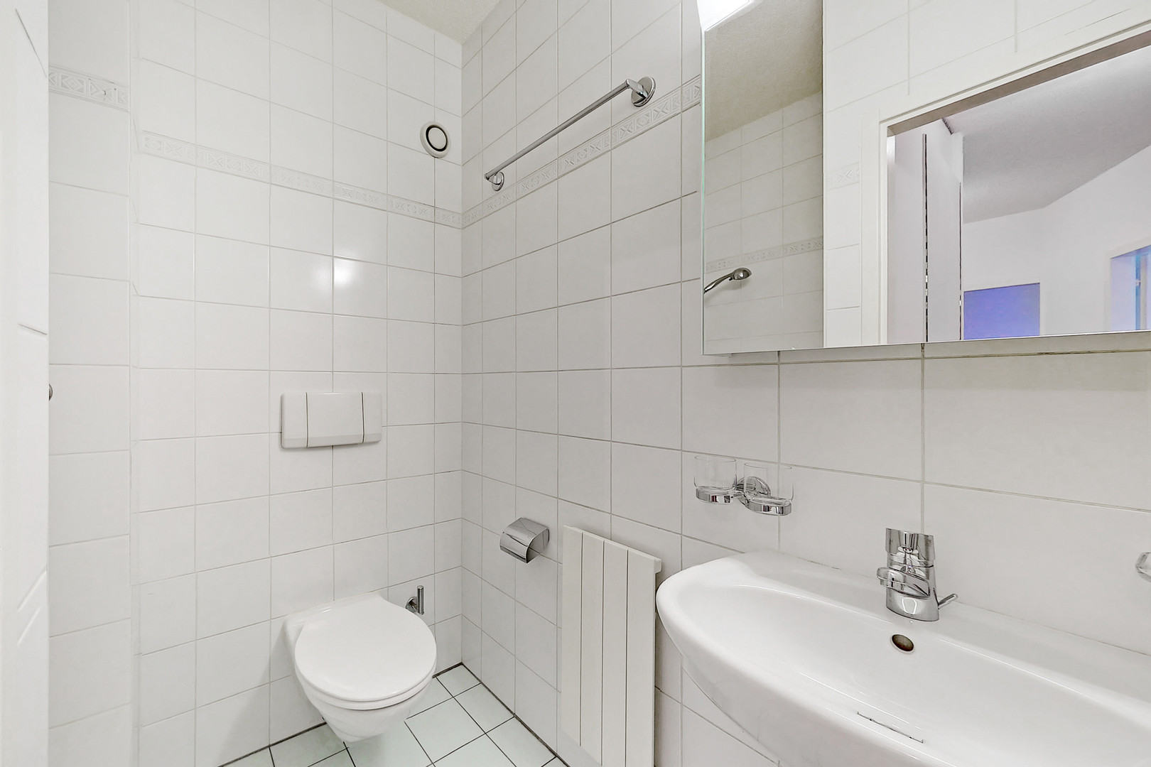 Kleines weiß gefliestes Gäste-WC mit Waschbecken und WC
