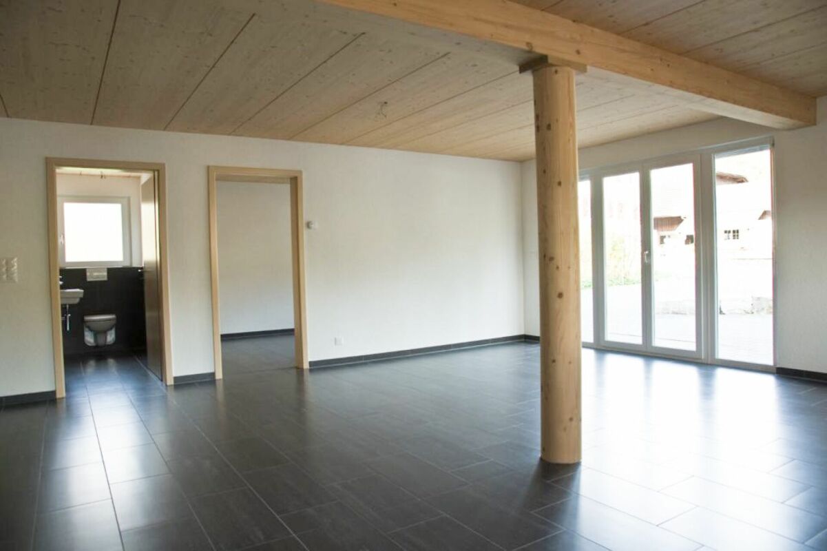 Offener Wohnraum mit Holzstütze und Fliesenboden