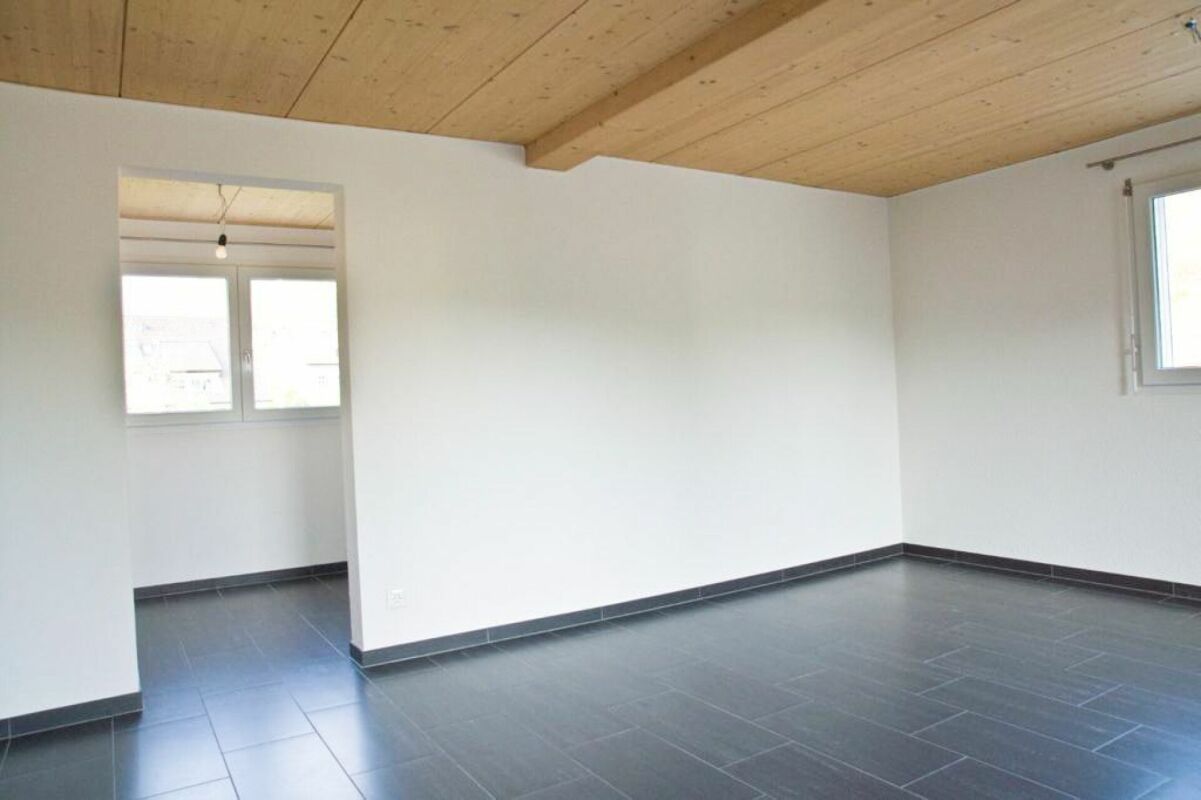 Leerer Raum mit Holzdecke und dunklem Fliesenboden