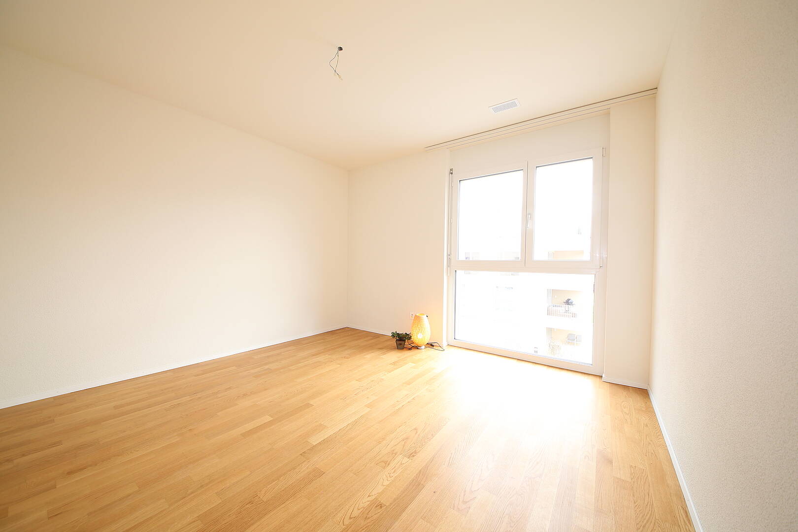 Heller leerer Raum mit Holzfußboden und großem Fenster