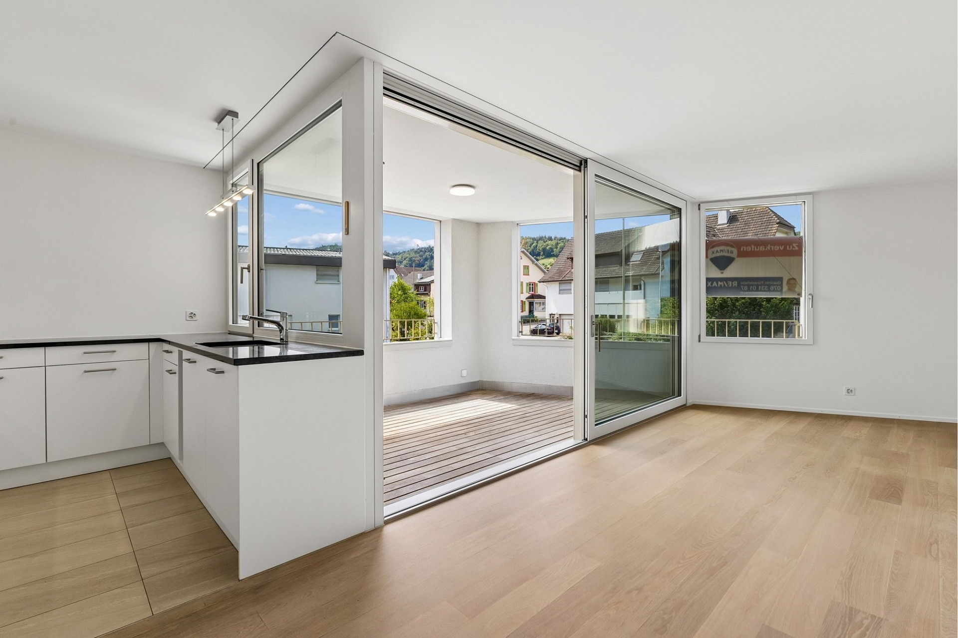 Offener Wohnbereich mit Küche und verglastem Übergang zum Balkon