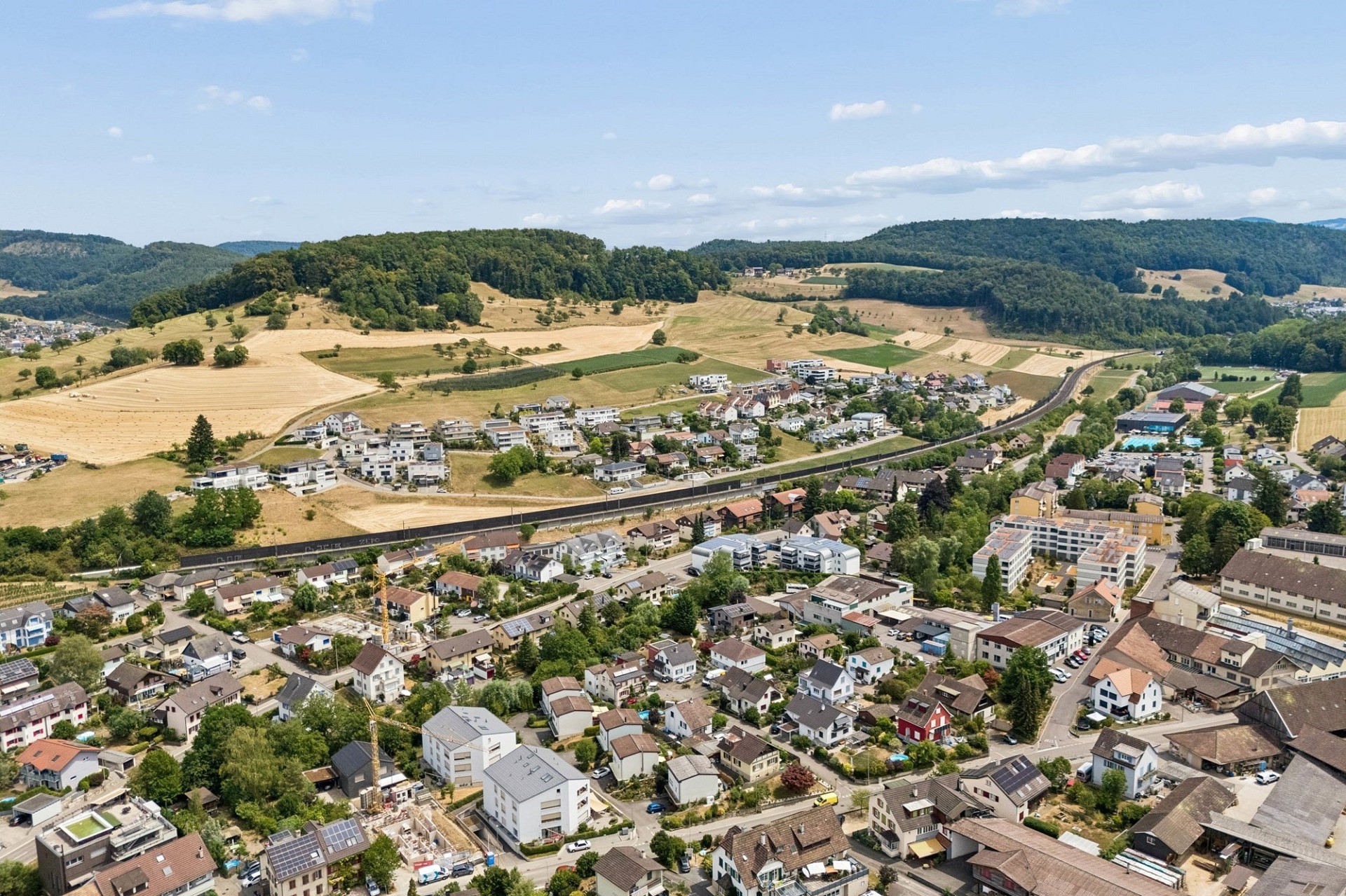Luftaufnahme eines Vororts in grüner Tallandschaft