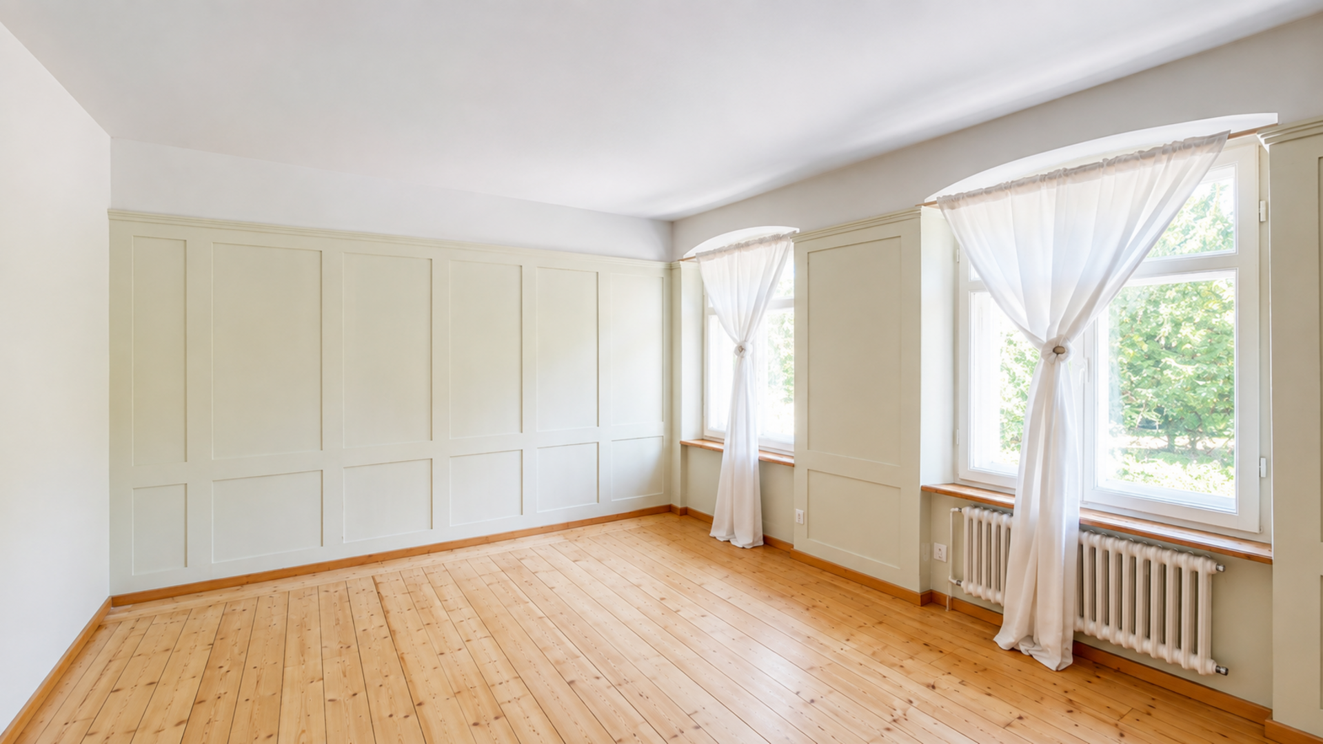 Heller leerer Wohnraum mit Holzfußboden und Wandpaneelen