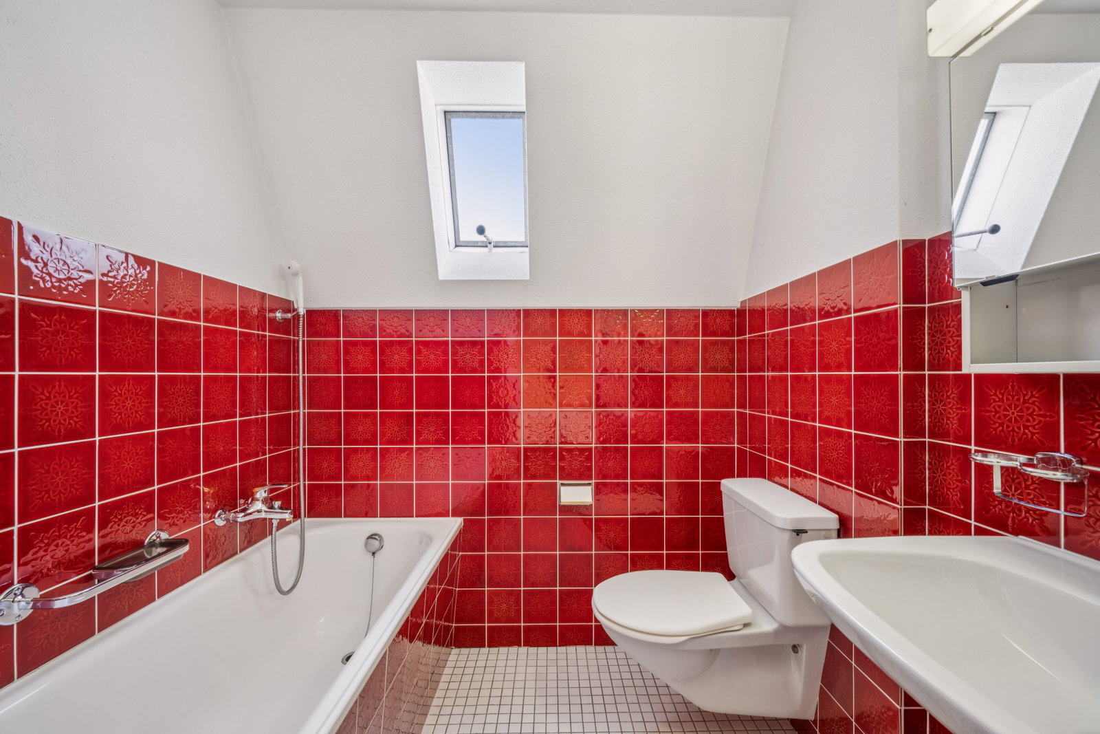 Badezimmer mit roter Fliesenverkleidung und Dachfenster