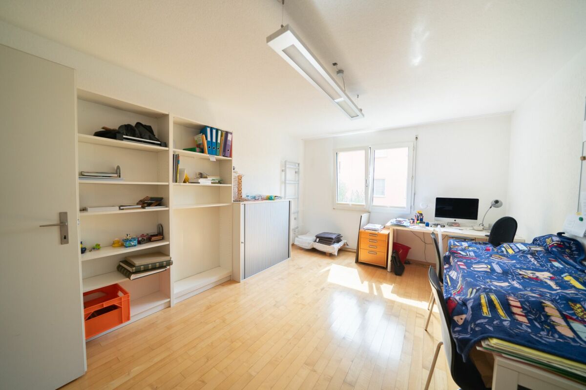 Helles Kinder- oder Arbeitszimmer mit Bett, Schreibtisch und Regalen