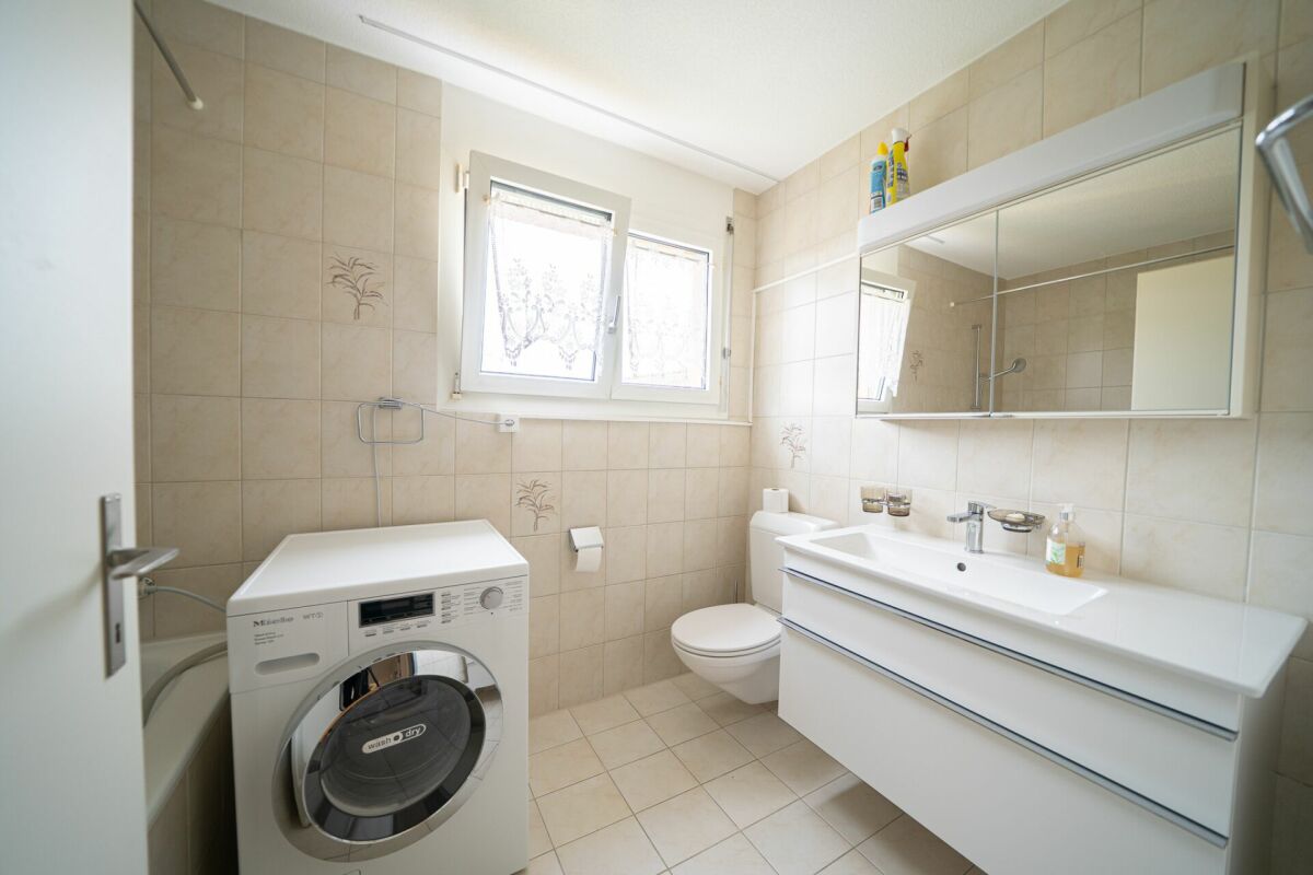Helles Badezimmer mit Waschmaschine und Spiegelschrank