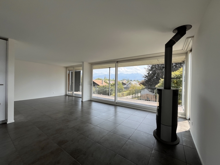Offener Wohnraum mit Panoramafenster und Kaminofen