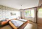 Helles Schlafzimmer mit Holzfenstern und gemachtem Bett