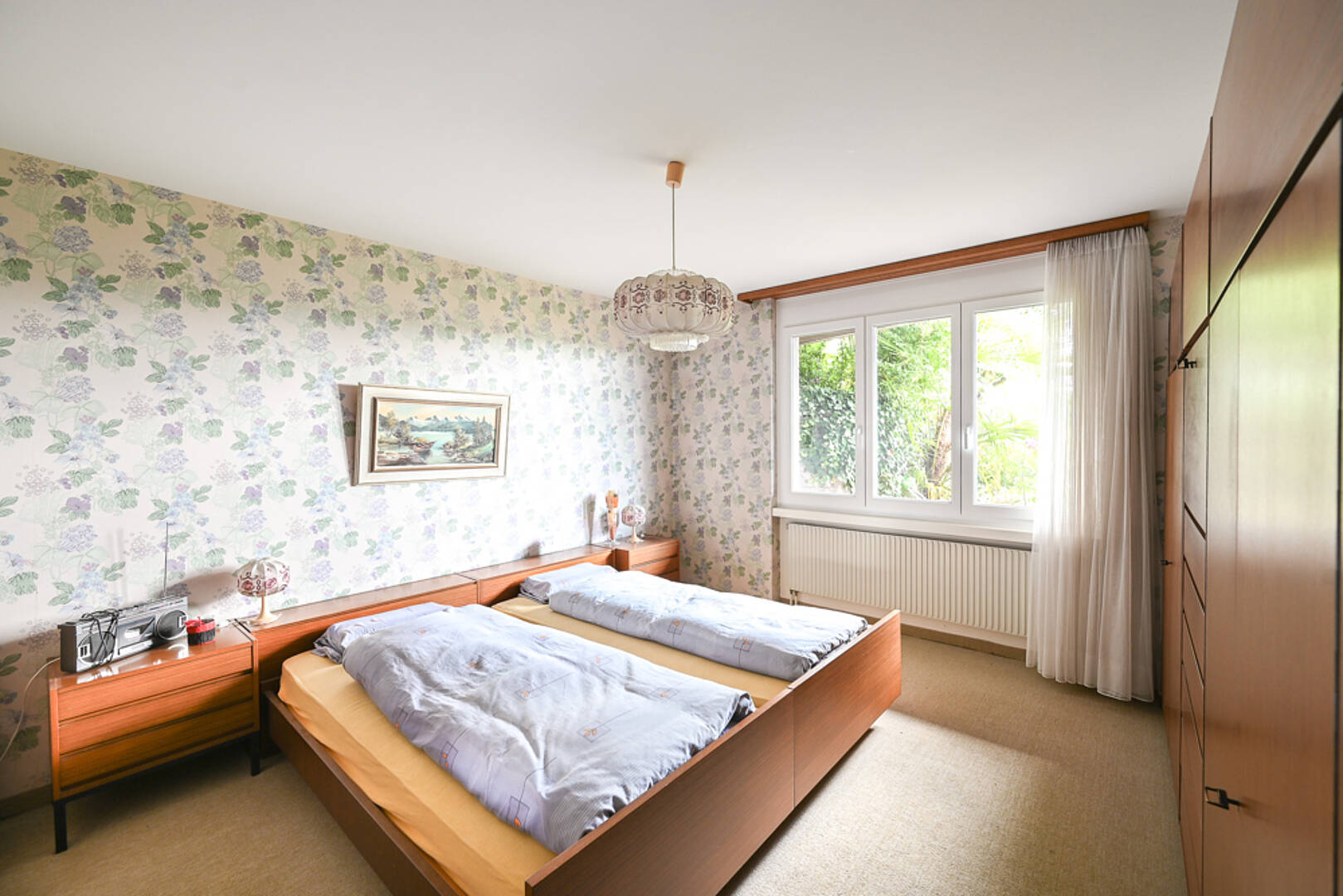 Schlafzimmer mit floraler Tapete und zwei Betten