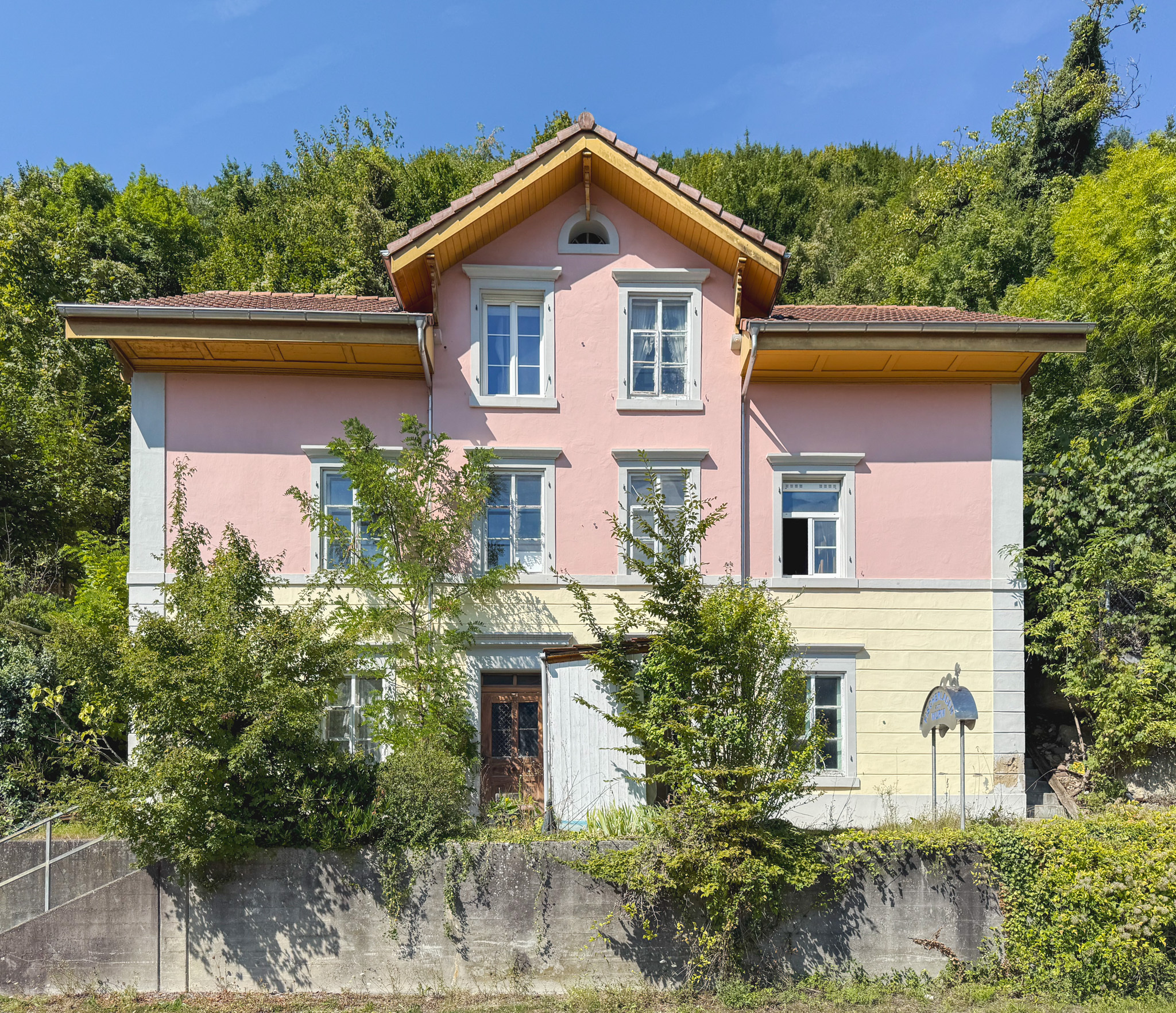 Pastellfarbene Villa mit Satteldach in grüner Hanglage