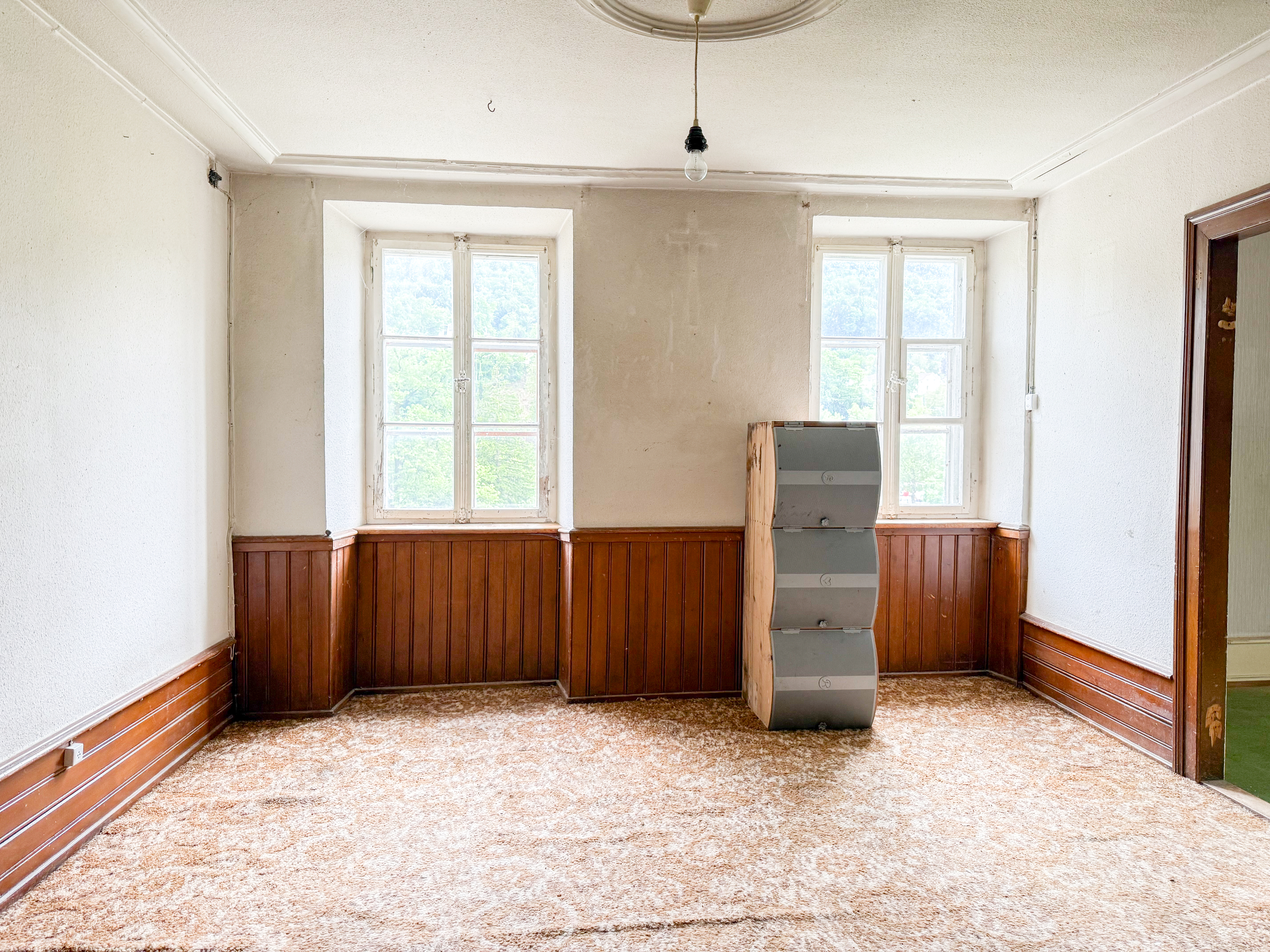 Leeres Zimmer mit Holzvertäfelung und zwei Fenstern