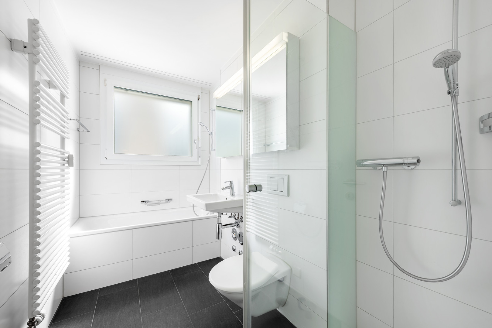 Modernes, helles Badezimmer mit Badewanne und Duschzone