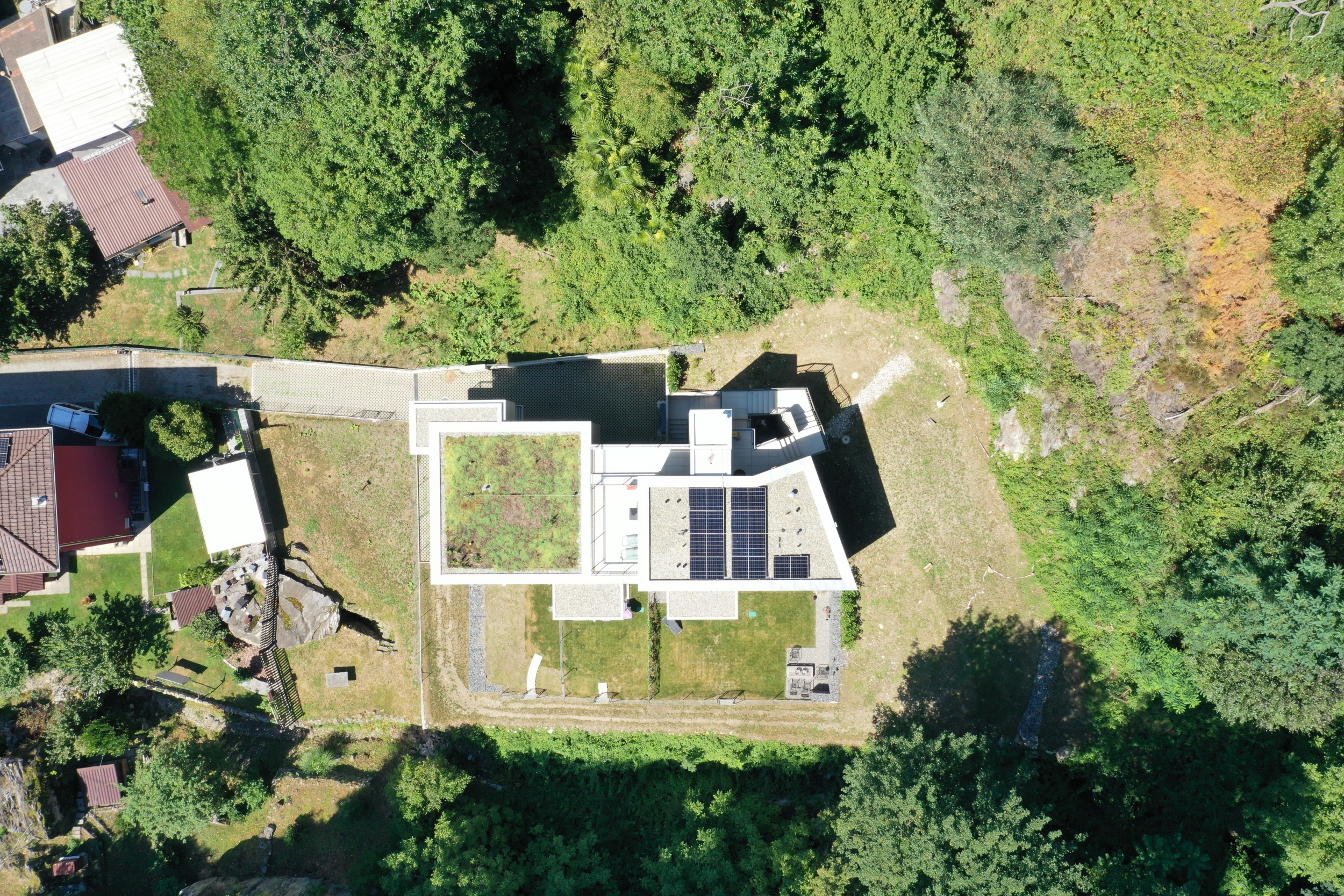 Luftaufnahme eines Hauses mit begrüntem Flachdach und Solarpaneelen