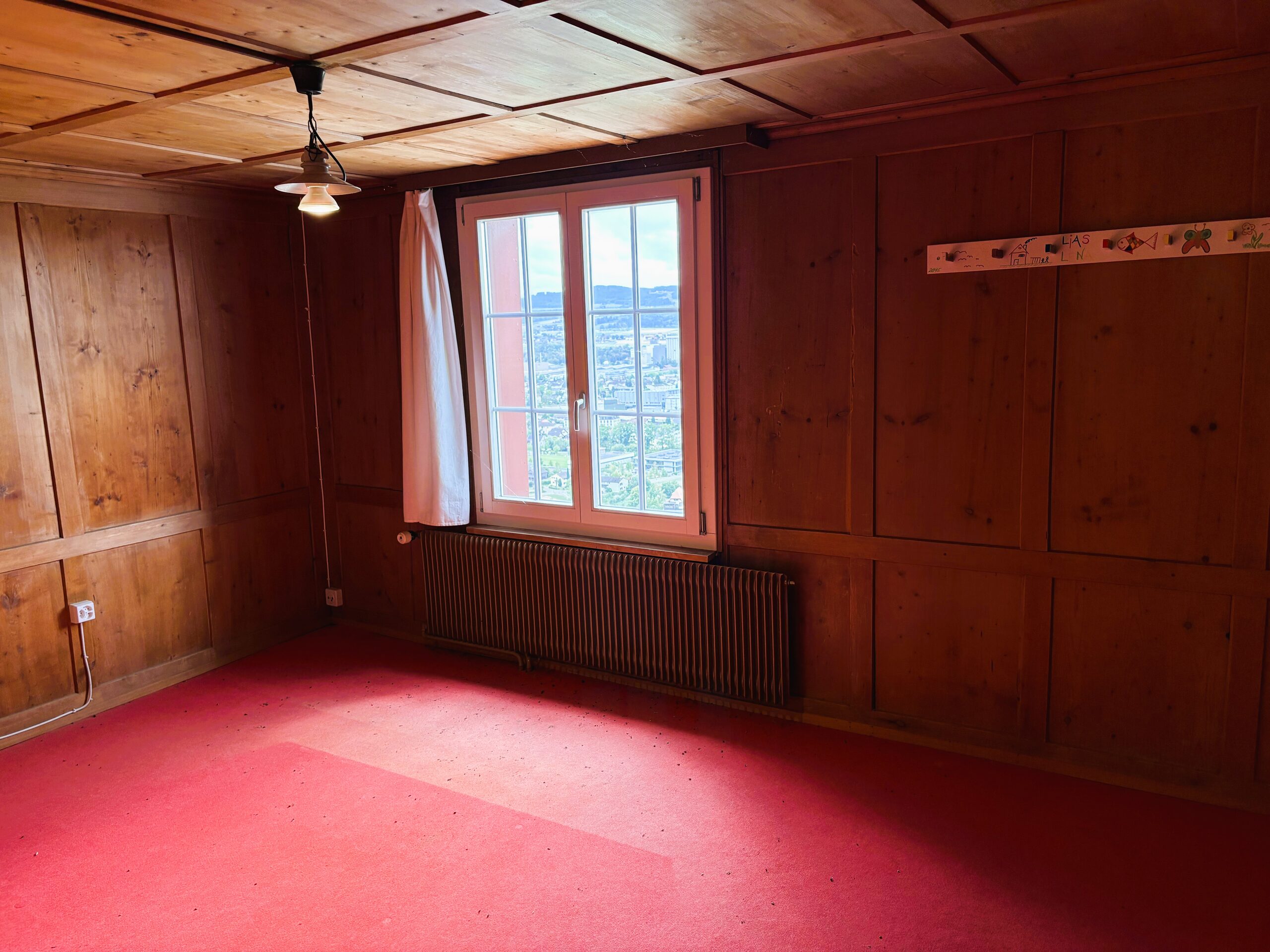 Holzverkleideter Raum mit Fenster und Heizkörper