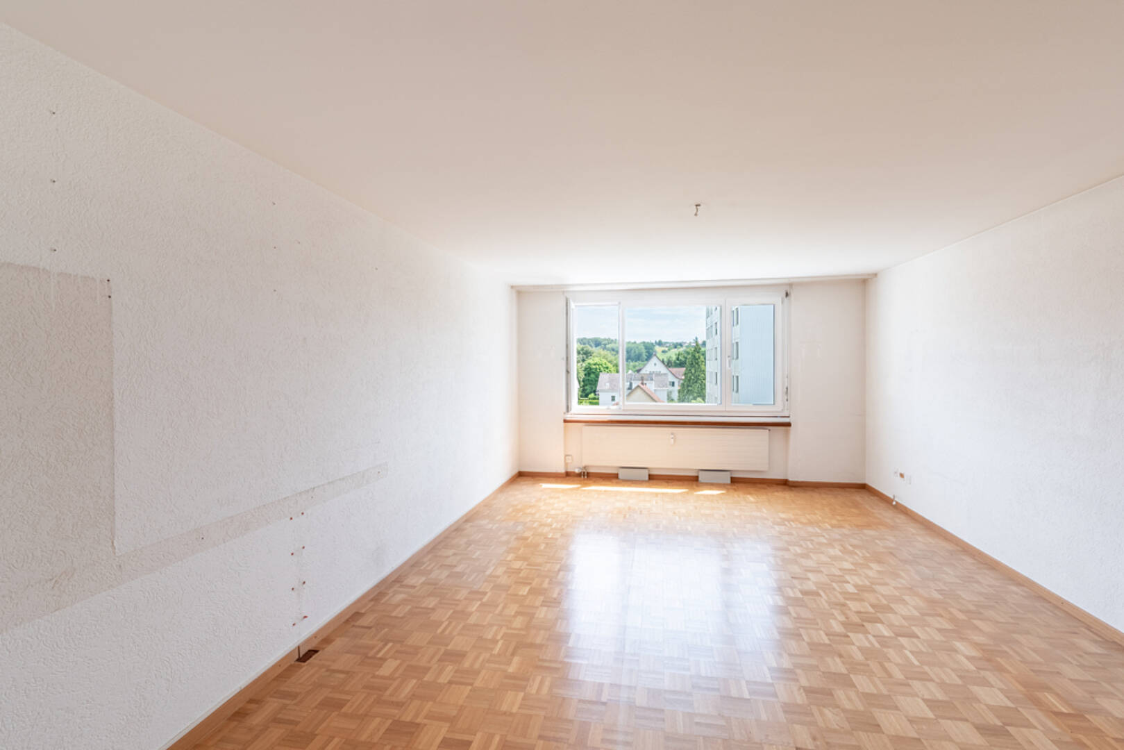 Leerer Wohnraum mit Parkett und Fensterblick