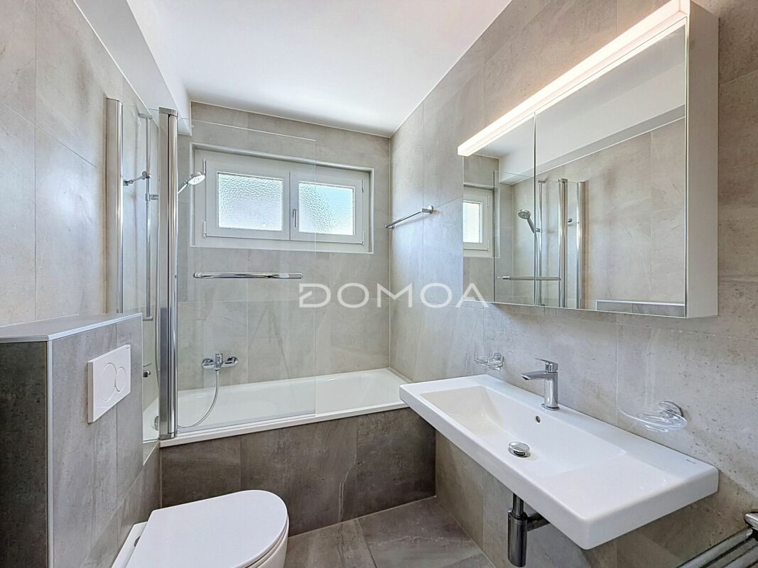 Modernes Badezimmer mit Badewanne, Waschtisch und Spiegel