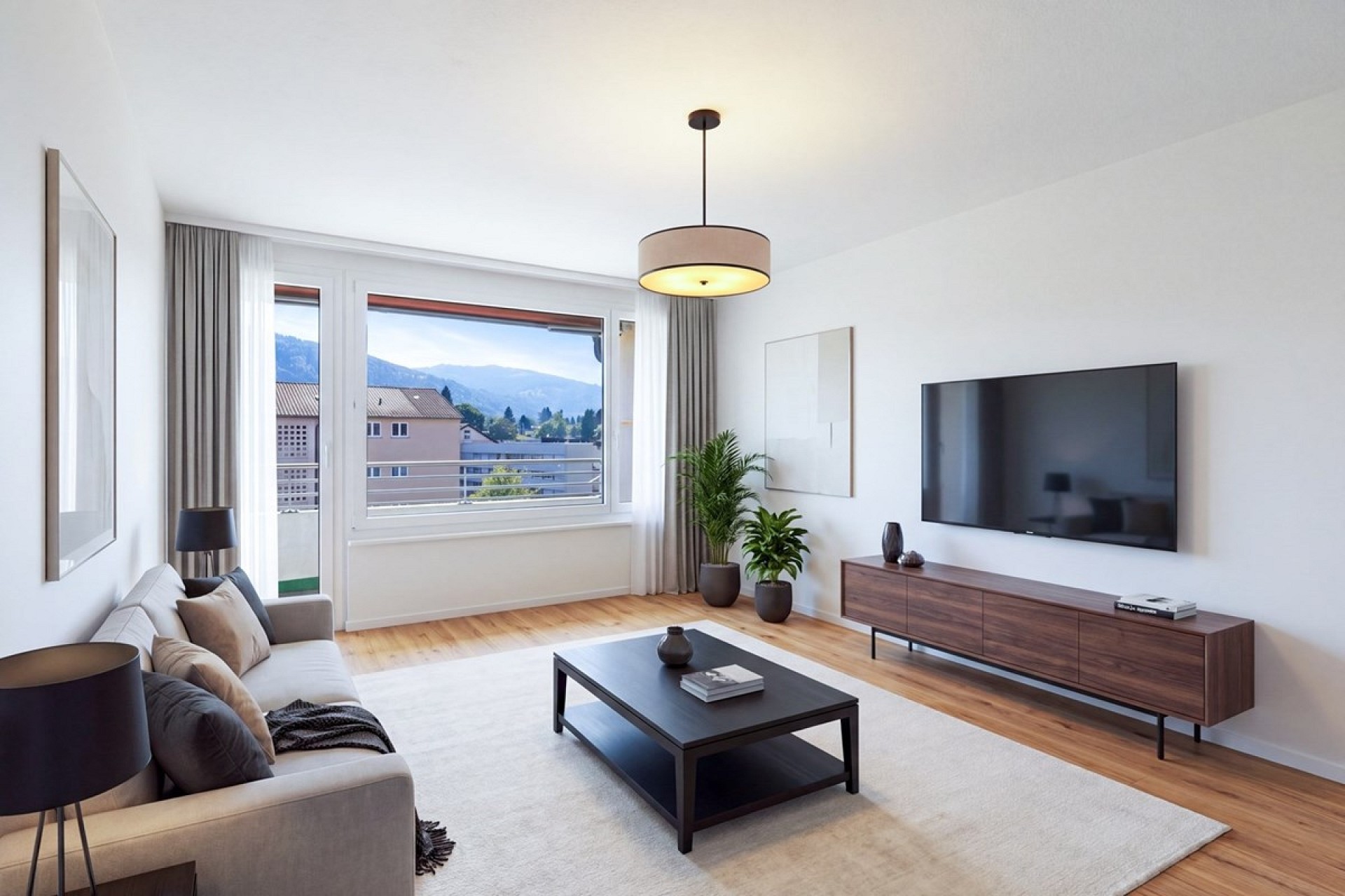 Hell eingerichtetes Wohnzimmer mit Bergblick