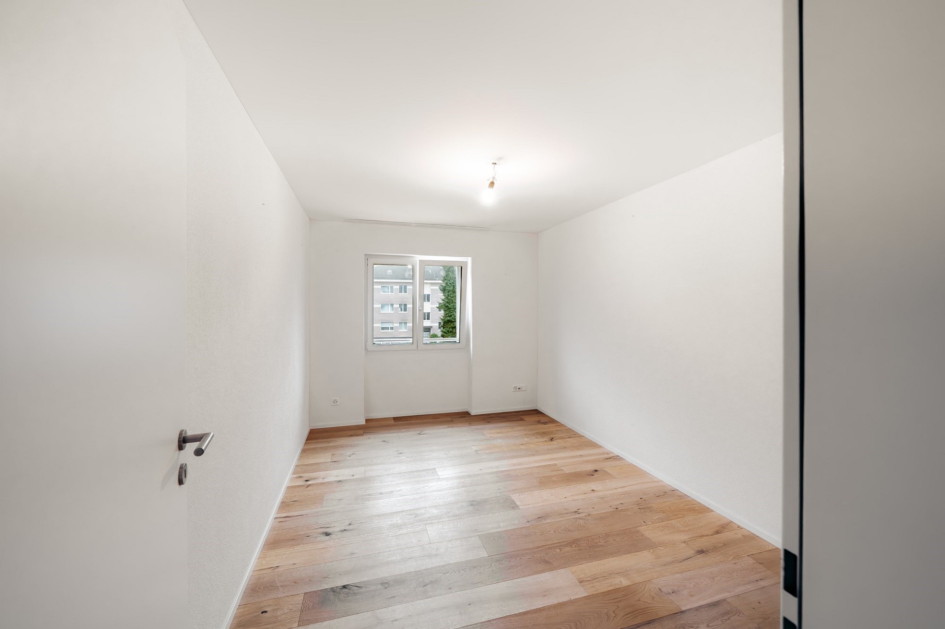 Helles, leeres Zimmer mit Parkettboden