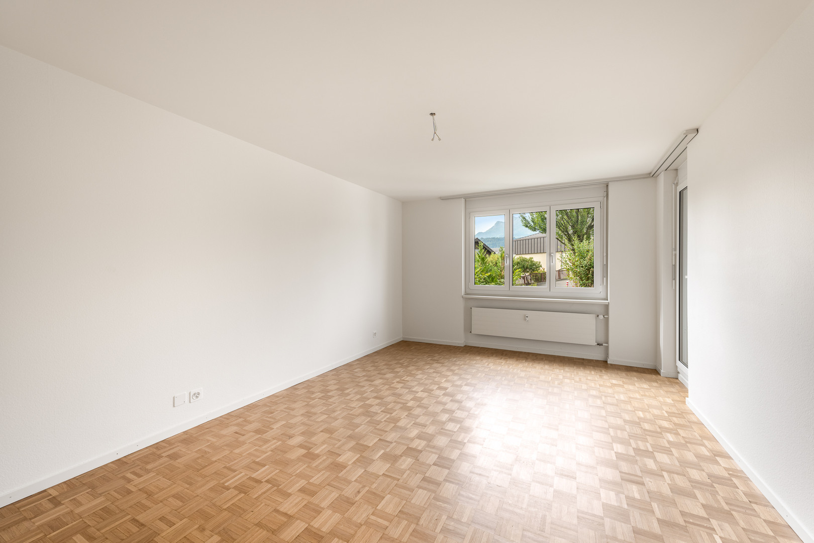 Heller leerer Raum mit Parkett und Fensterblick