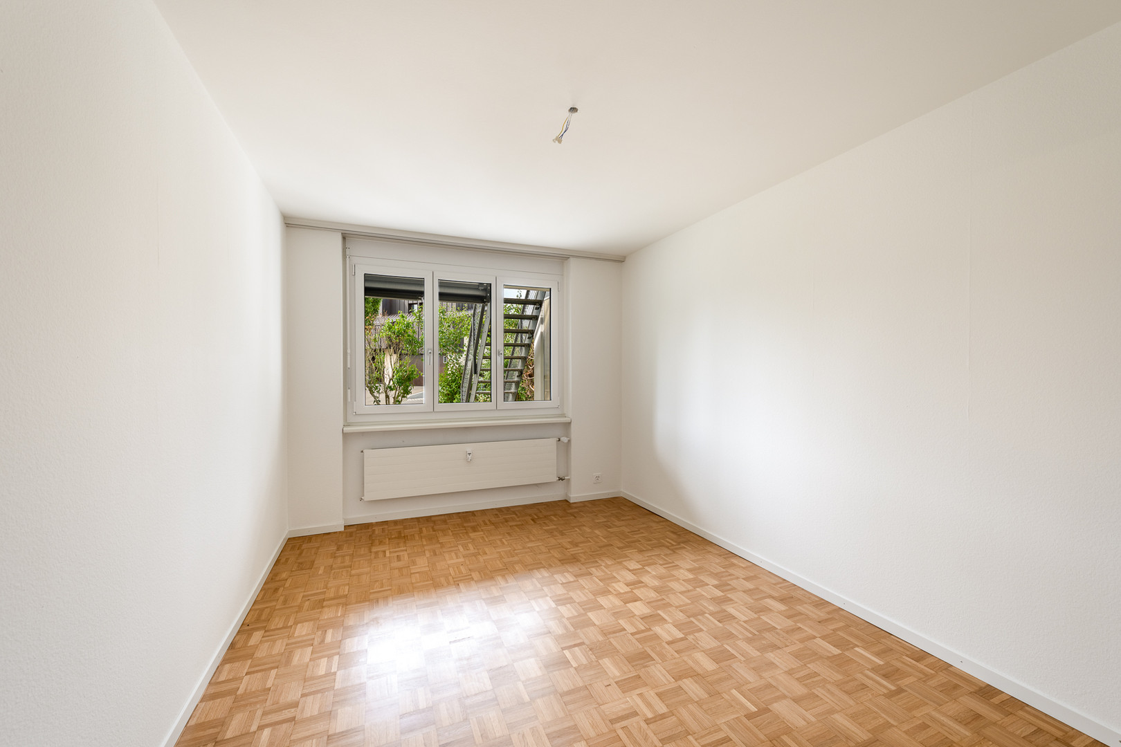 Leeres Zimmer mit Fenster und Parkettboden