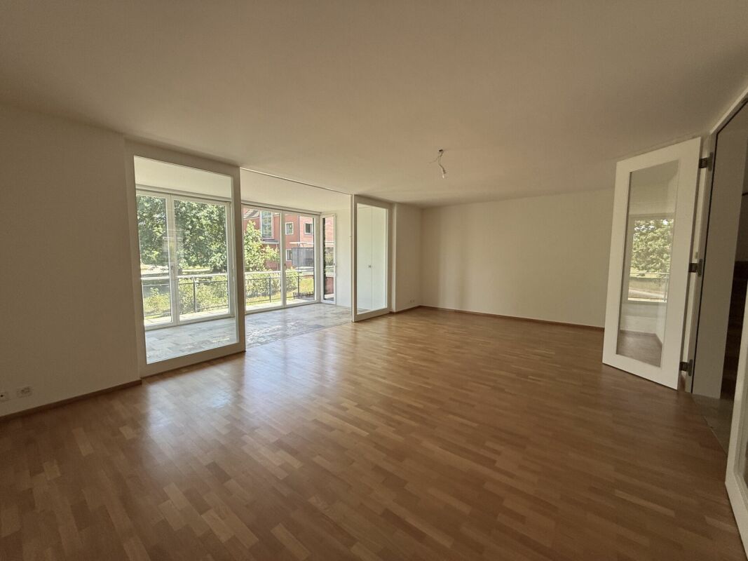 Großer leerer Wohnraum mit Balkonzugang