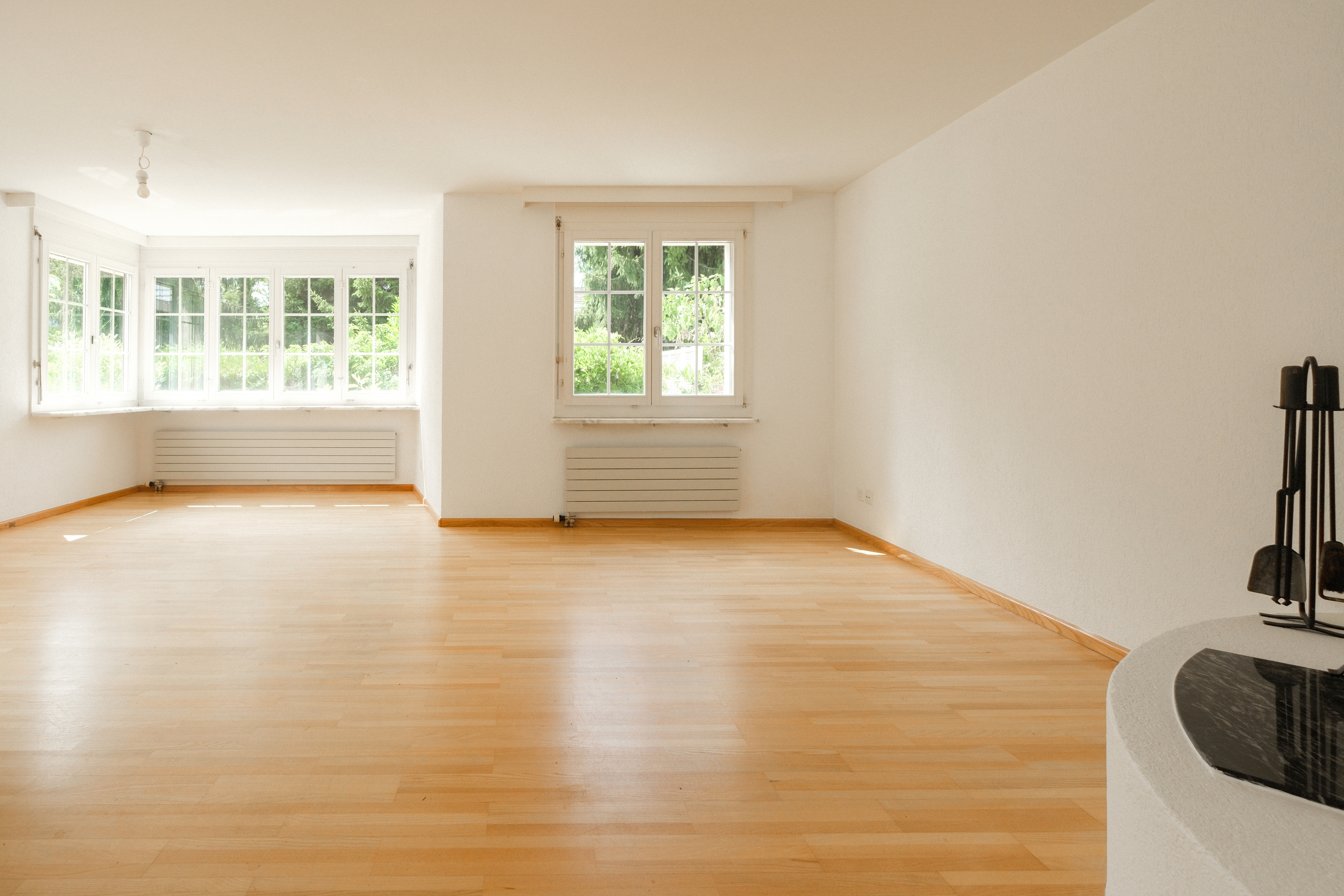 Heller leerer Wohnraum mit Fenstern und Parkettboden