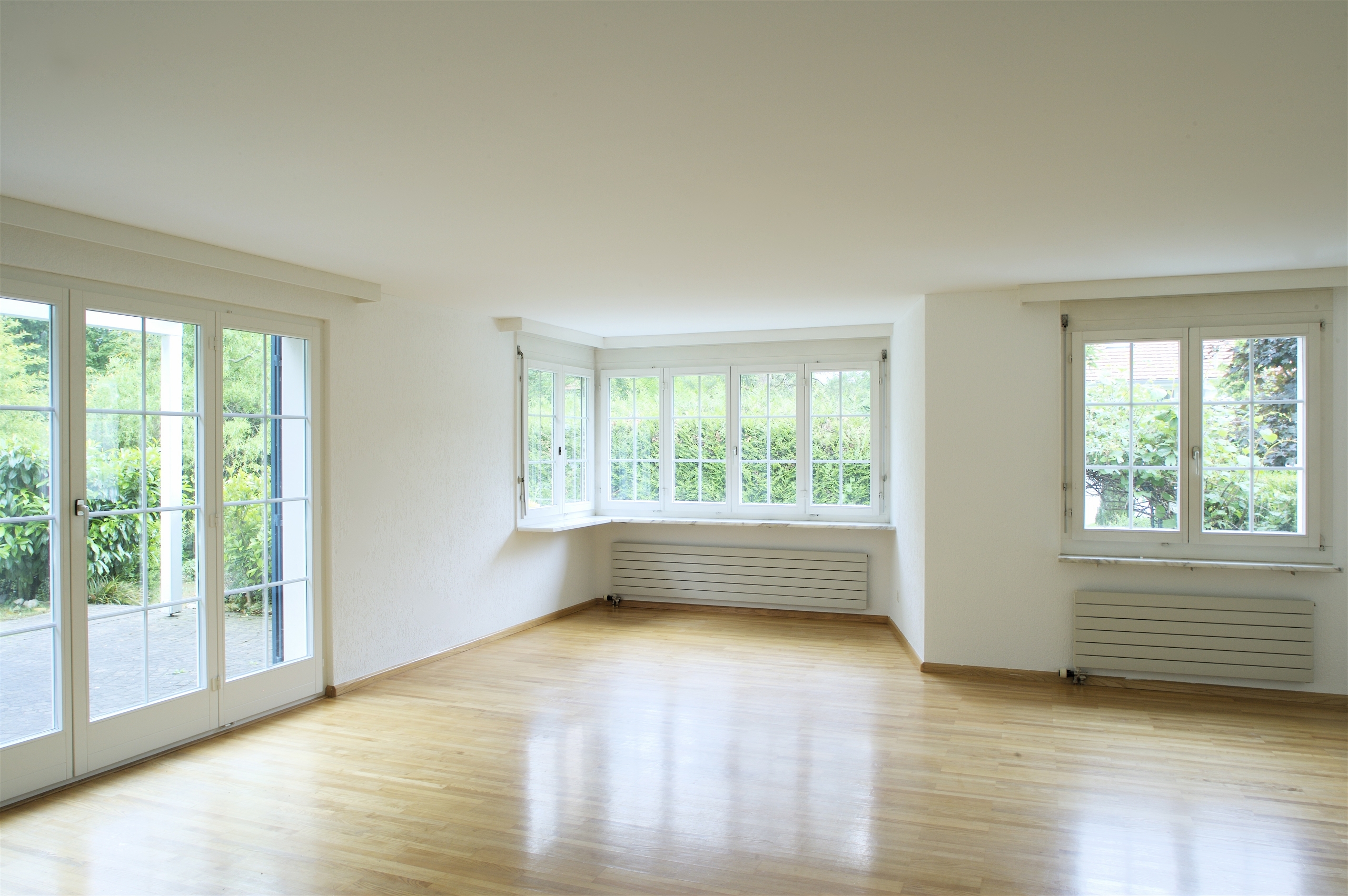 Helles leerstehendes Wohnzimmer mit vielen Fenstern