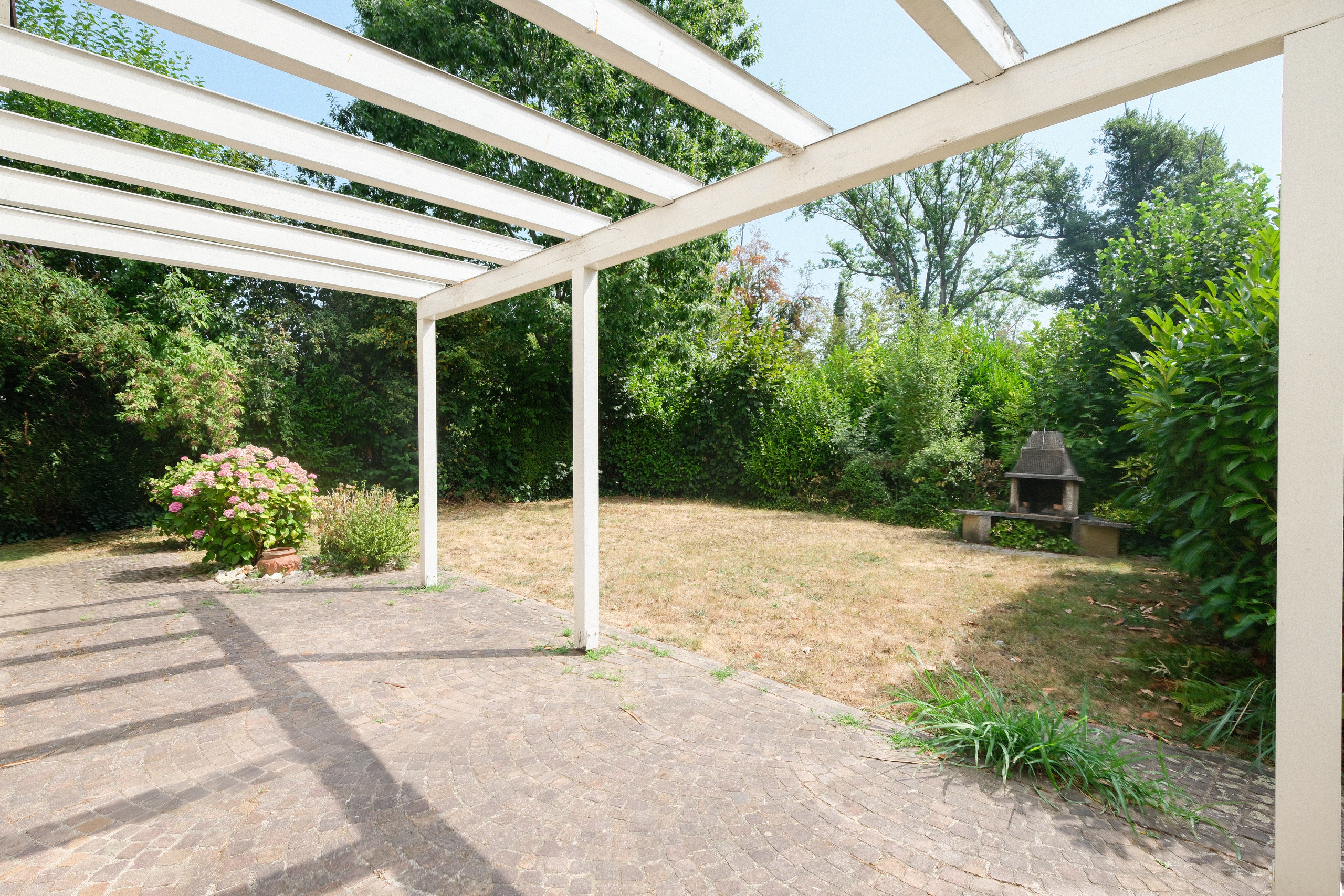 Gepflasterte Terrasse mit Pergola und Gartenblick