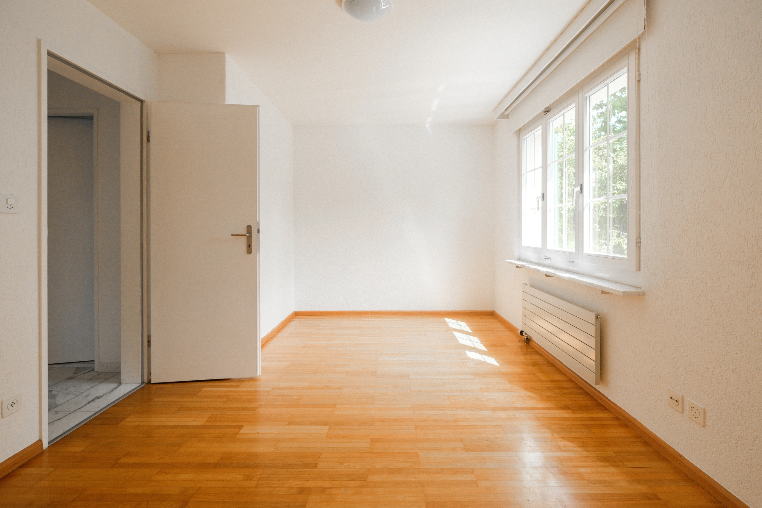 Heller leerer Raum mit Fenster und offener Tür