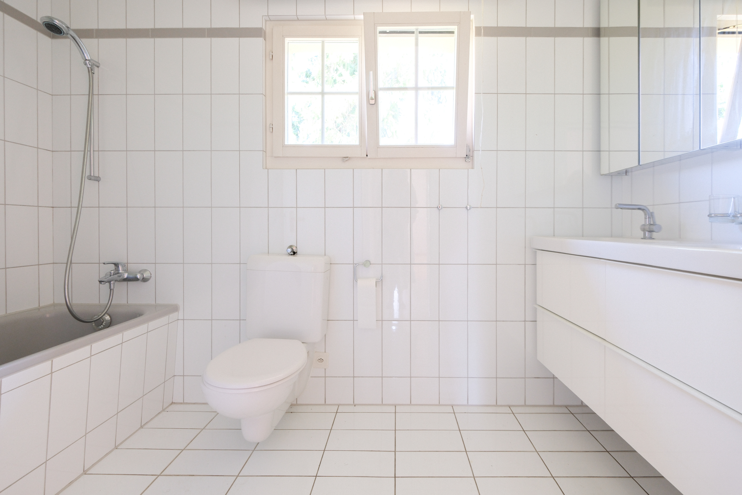 Helles, schlichtes Badezimmer mit Badewanne, WC und Waschtisch