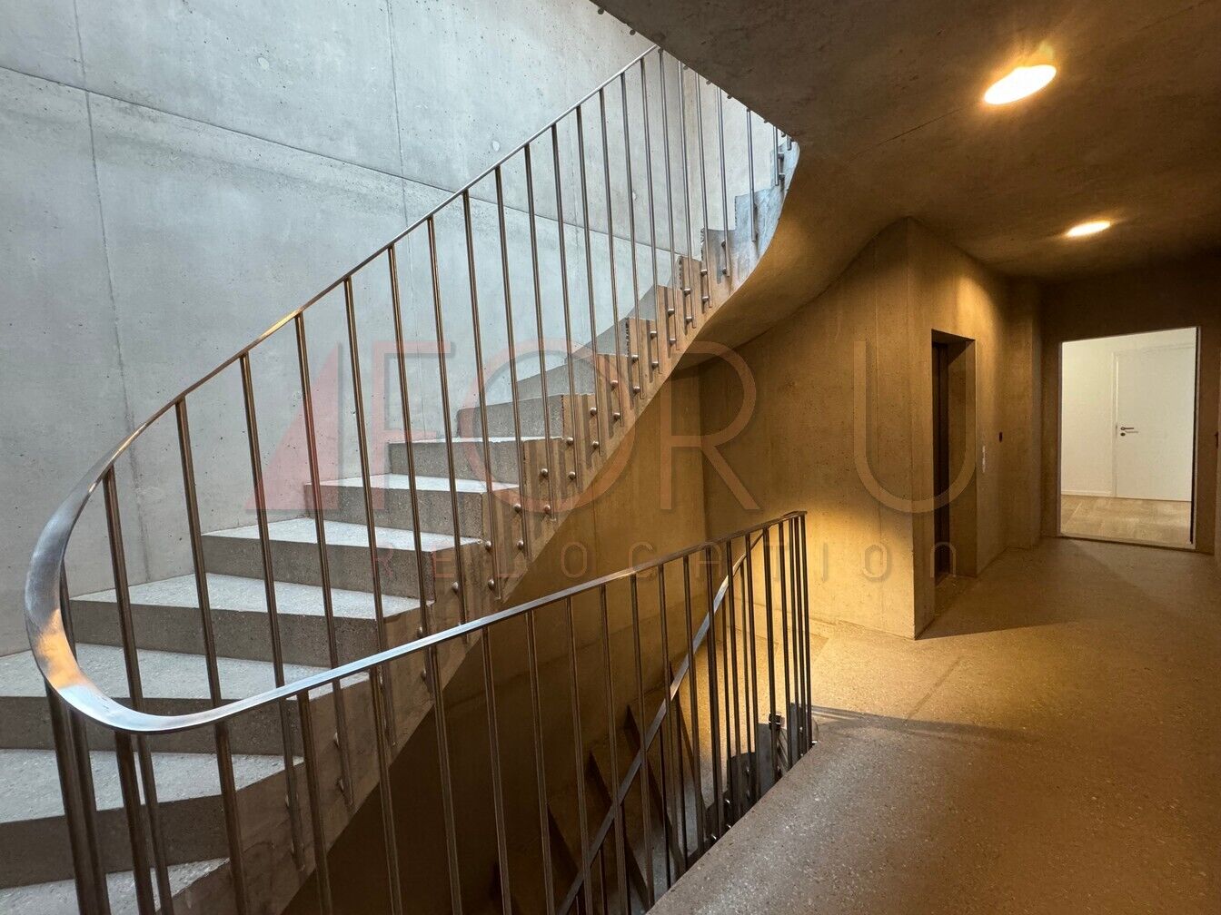 Trepppenhaus mit Sichtbeton und gebogenem Geländer