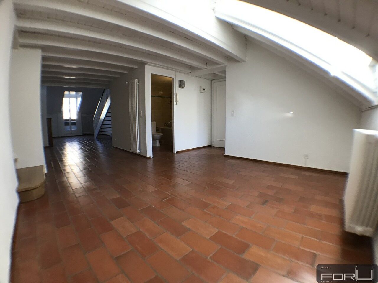 Dachgeschossraum mit Ziegelboden und sichtbaren Holzbalken
