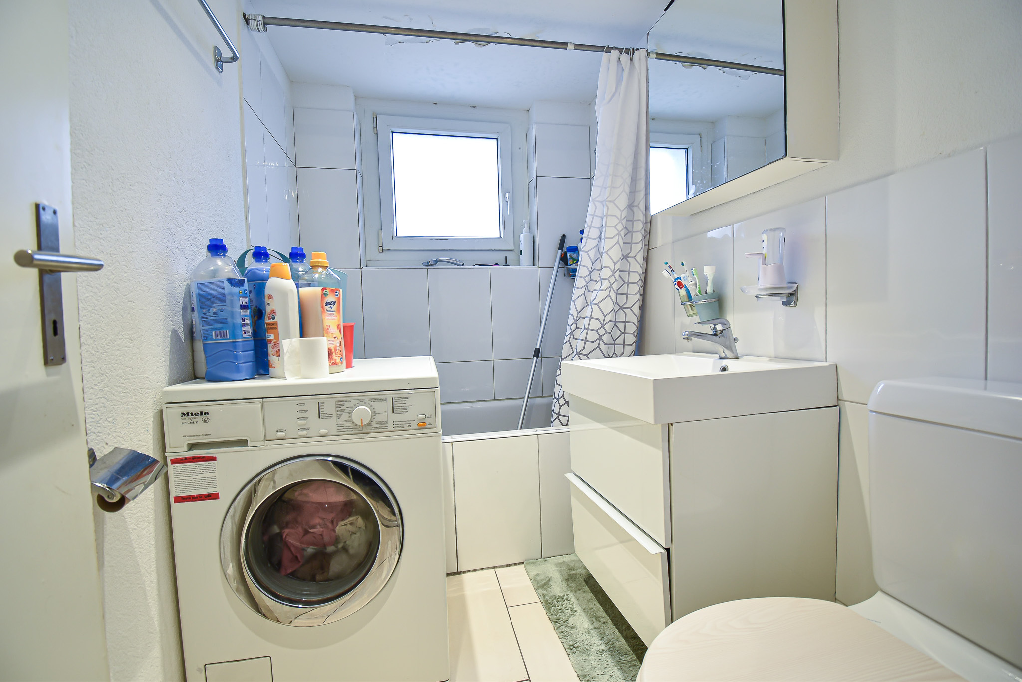 Kleines Badezimmer mit Badewanne und Waschmaschine