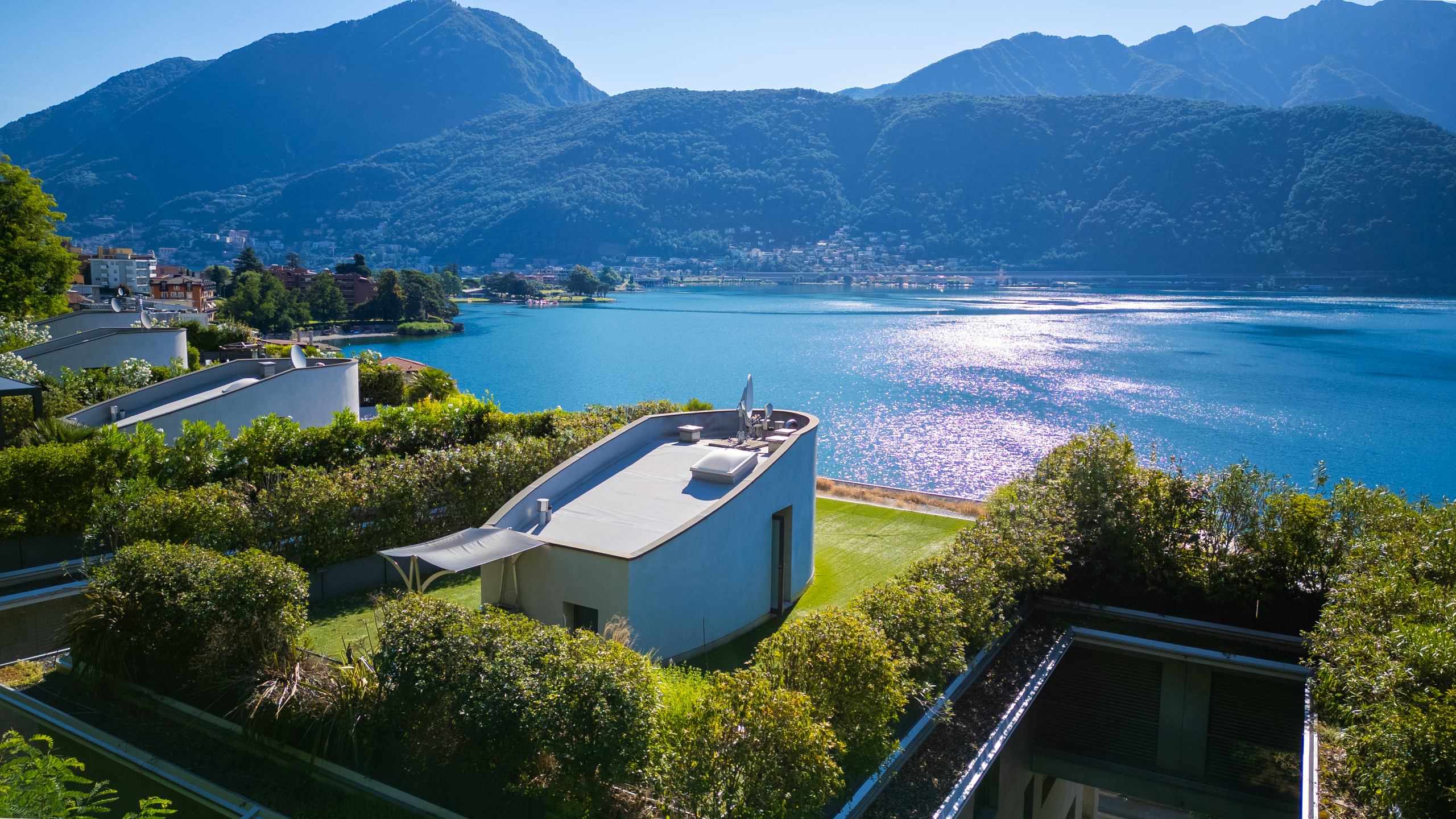 Seeblick mit begrünten Terrassen und Flachdachgebäuden