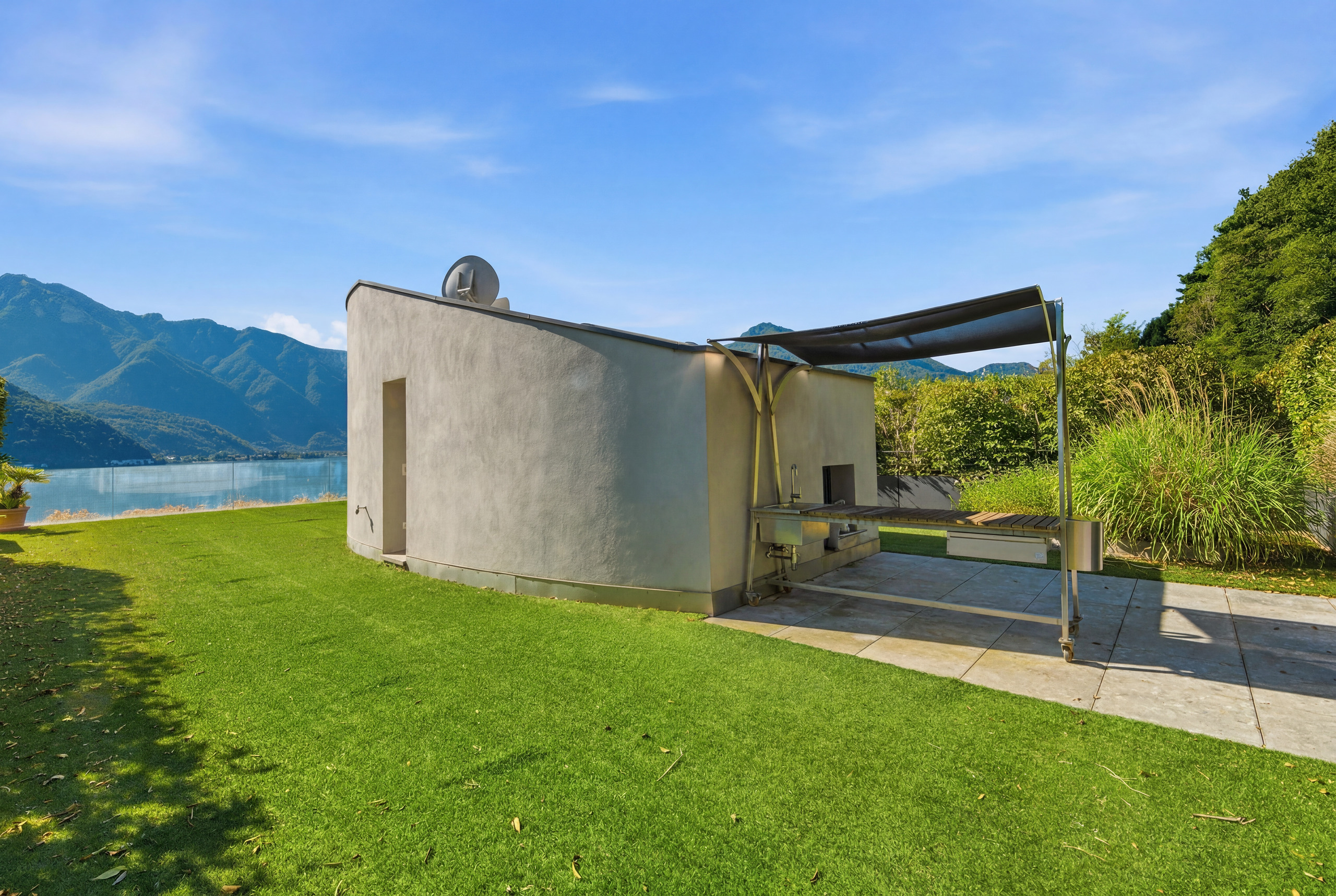 Modernes Außengelände mit kompakter Outdoor-Küche und Seeblick